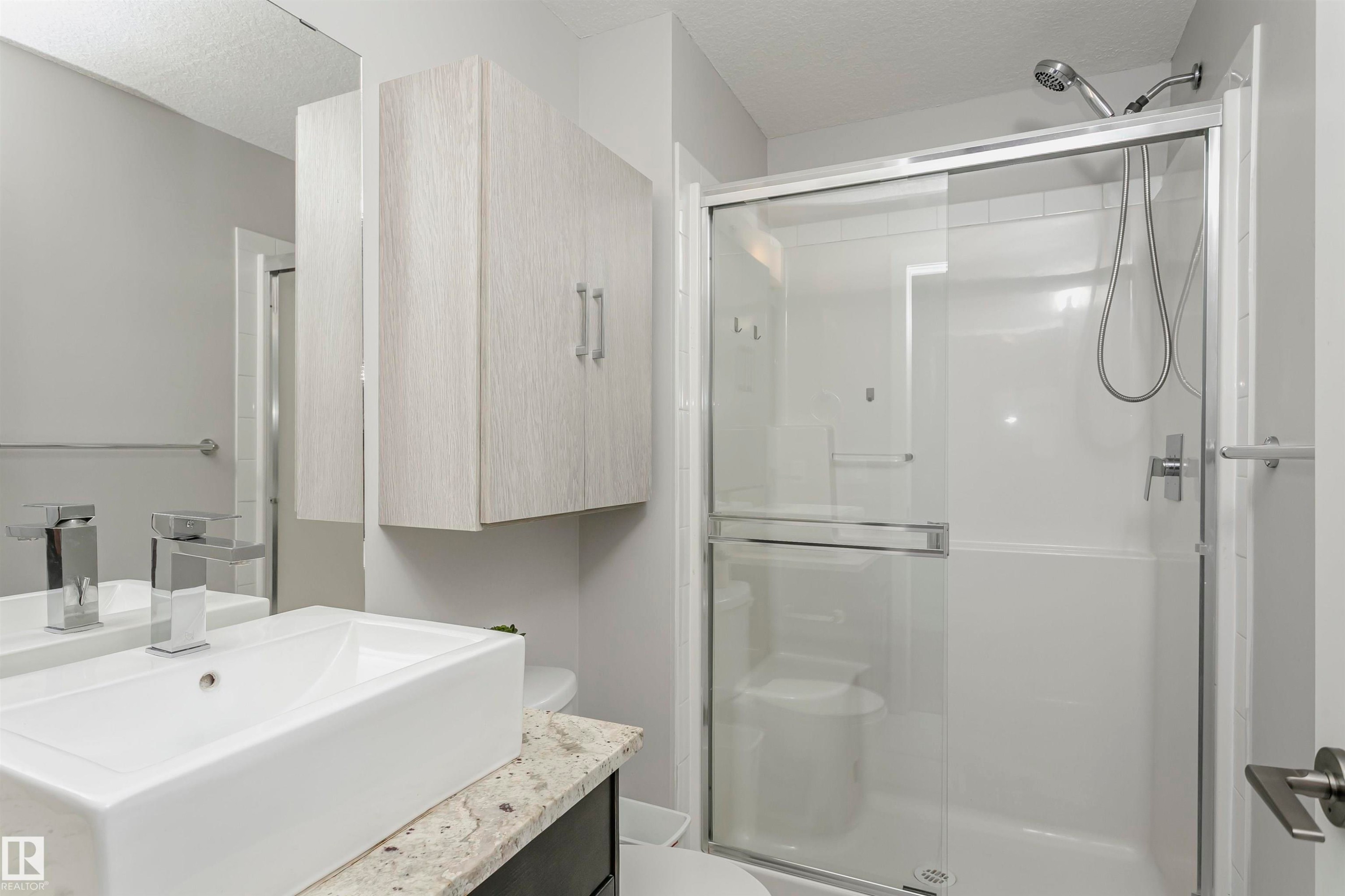 Full bathroom with a shower stall, vanity, and a textured ceiling - 332 5151 Windermere Boulevard, Edmonton, AB - Indoor Photo Showing Bathroom