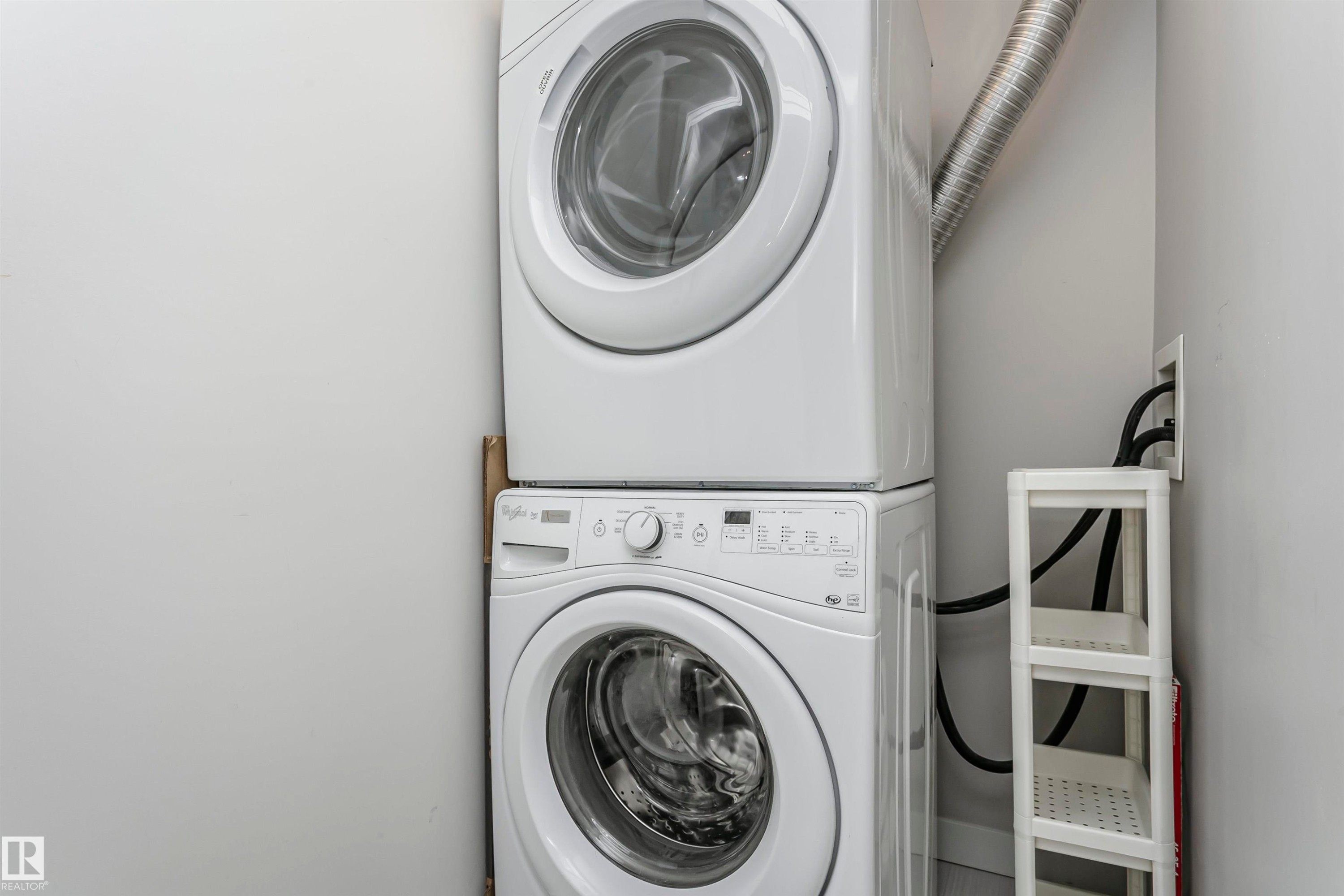 Laundry room featuring stacked washing machine and dryer - 332 5151 Windermere Boulevard, Edmonton, AB - Indoor Photo Showing Laundry Room