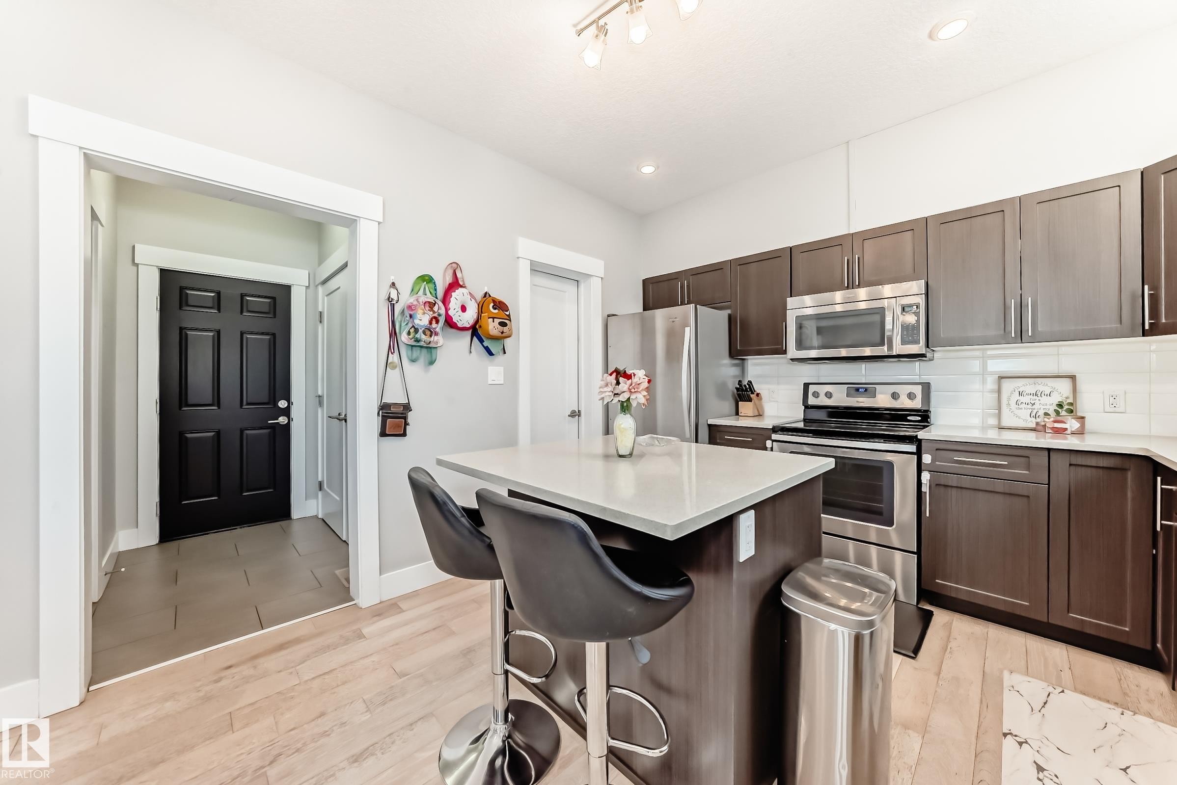 Kitchen featuring appliances with stainless steel finishes, a kitchen island, decorative backsplash, a kitchen bar, and light wood finished floors - 41 4835 Wright Drive, Edmonton, AB - Indoor Photo Showing Kitchen With Stainless Steel Kitchen With Double Sink