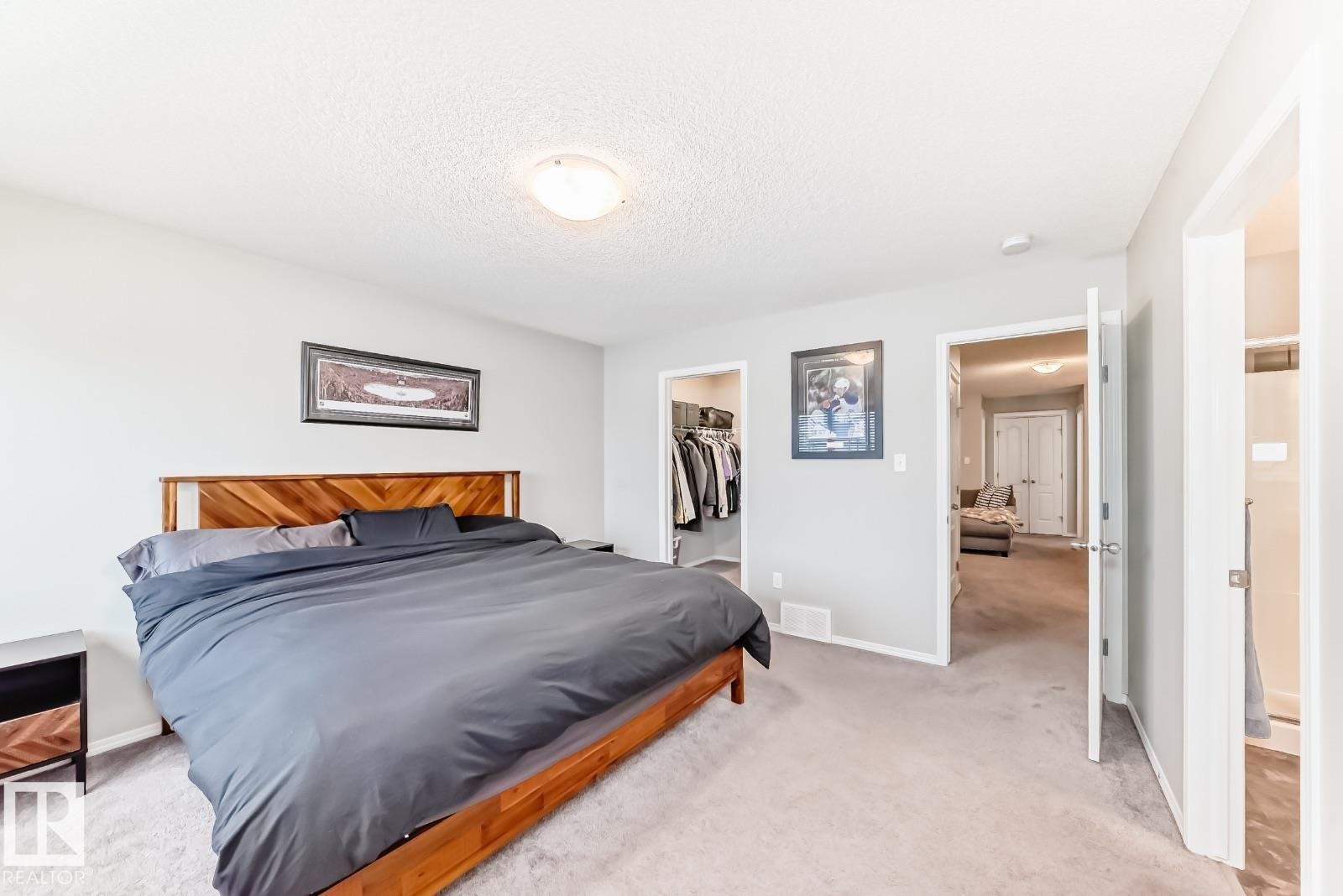 Bedroom featuring light carpet, a spacious closet, and a textured ceiling - 2823 Duke Crescent, Edmonton, AB - Indoor Photo Showing Bedroom