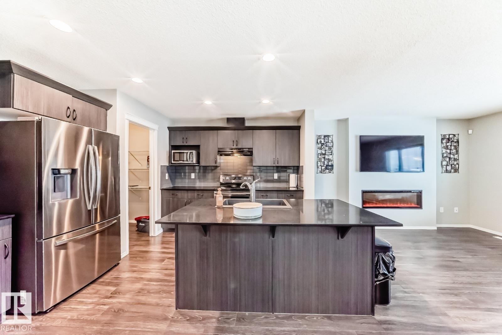 Kitchen with stainless steel appliances, light wood-type flooring, a kitchen breakfast bar, a kitchen island with sink, and backsplash - 2823 Duke Crescent, Edmonton, AB - Indoor Photo Showing Kitchen With Upgraded Kitchen