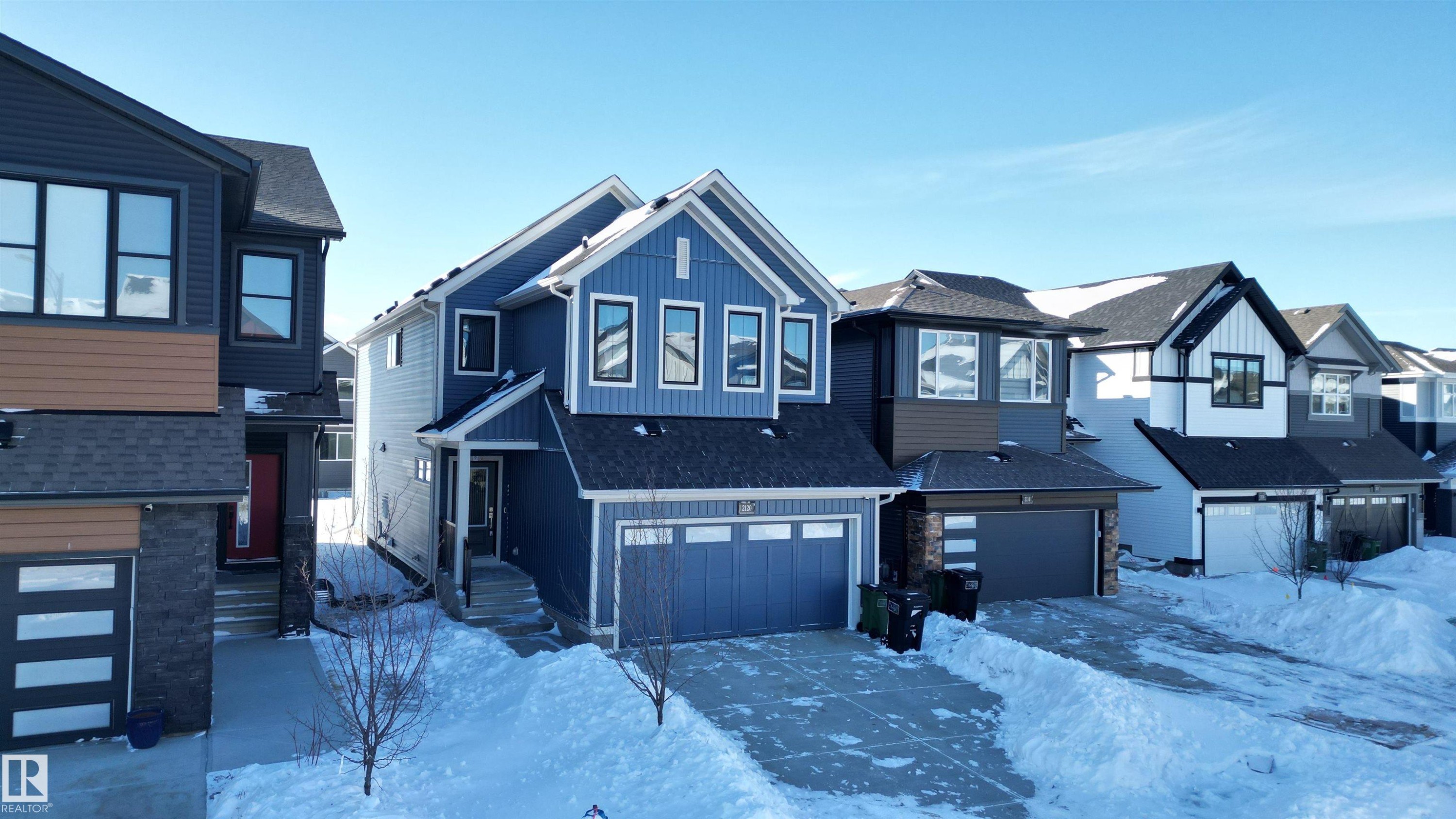 View of front of property with a residential view, an attached garage, board and batten siding, and a shingled roof - 2120 Muckleplum Crescent, Edmonton, AB - Outdoor With Facade