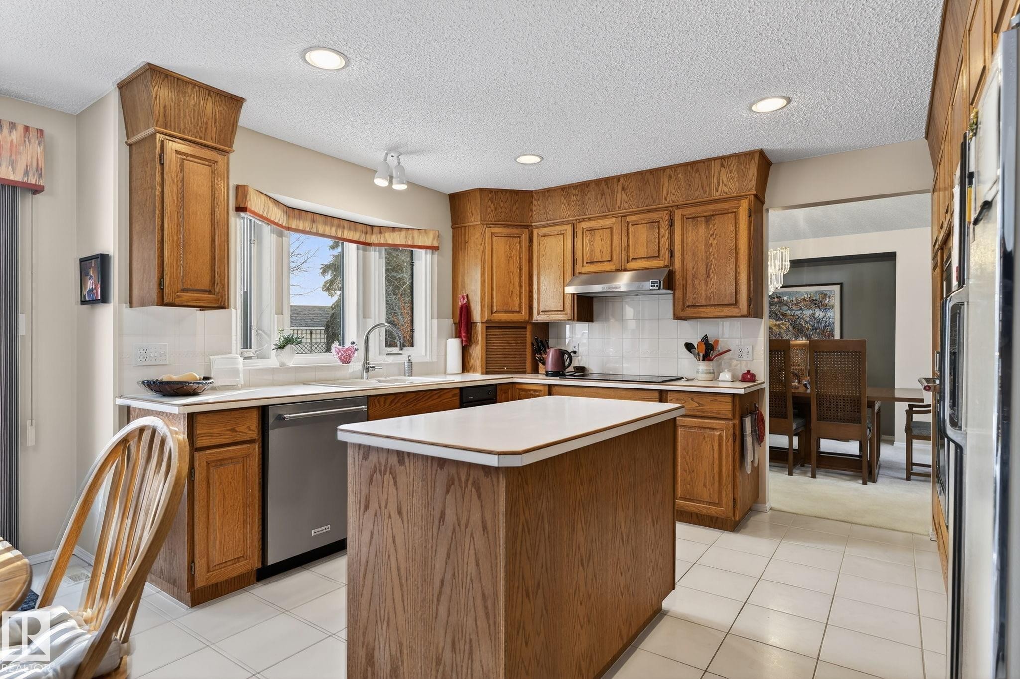 Kitchen with wood finish cabinets, light countertops, a kitchen island, recessed lighting, and stainless steel dishwasher - 313 Hedley Way, Edmonton, AB - Indoor Photo Showing Kitchen