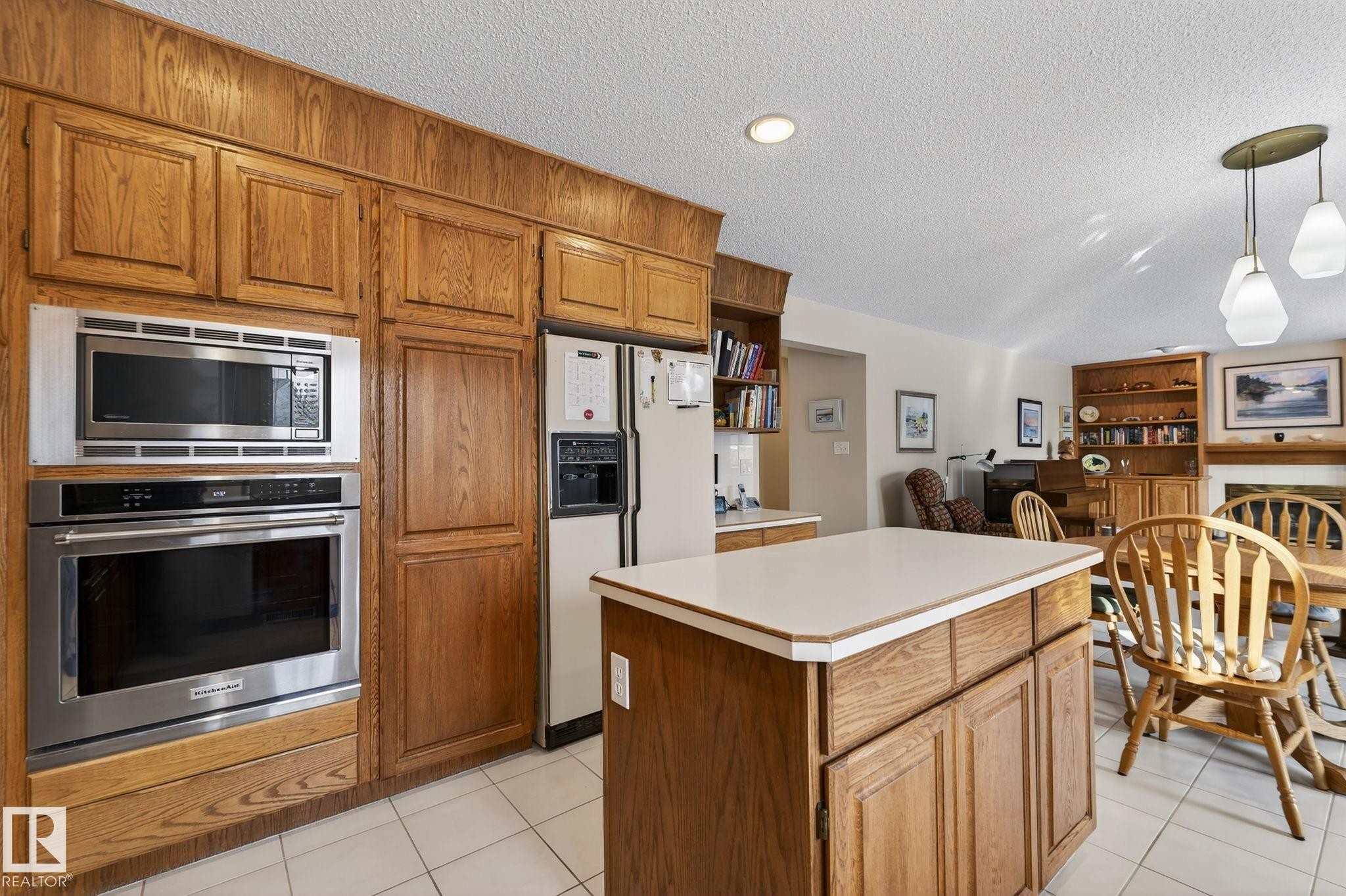 Kitchen with wood finish cabinetry, stainless steel appliances, light countertops, a center island, and open floor plan - 313 Hedley Way, Edmonton, AB - Indoor Photo Showing Kitchen
