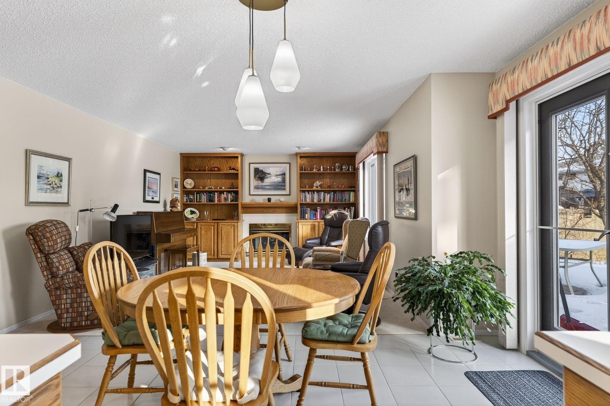 Dining room featuring a fireplace, a textured ceiling, and light tile patterned flooring - 313 Hedley Way, Edmonton, AB - Indoor Photo Showing Dining Room