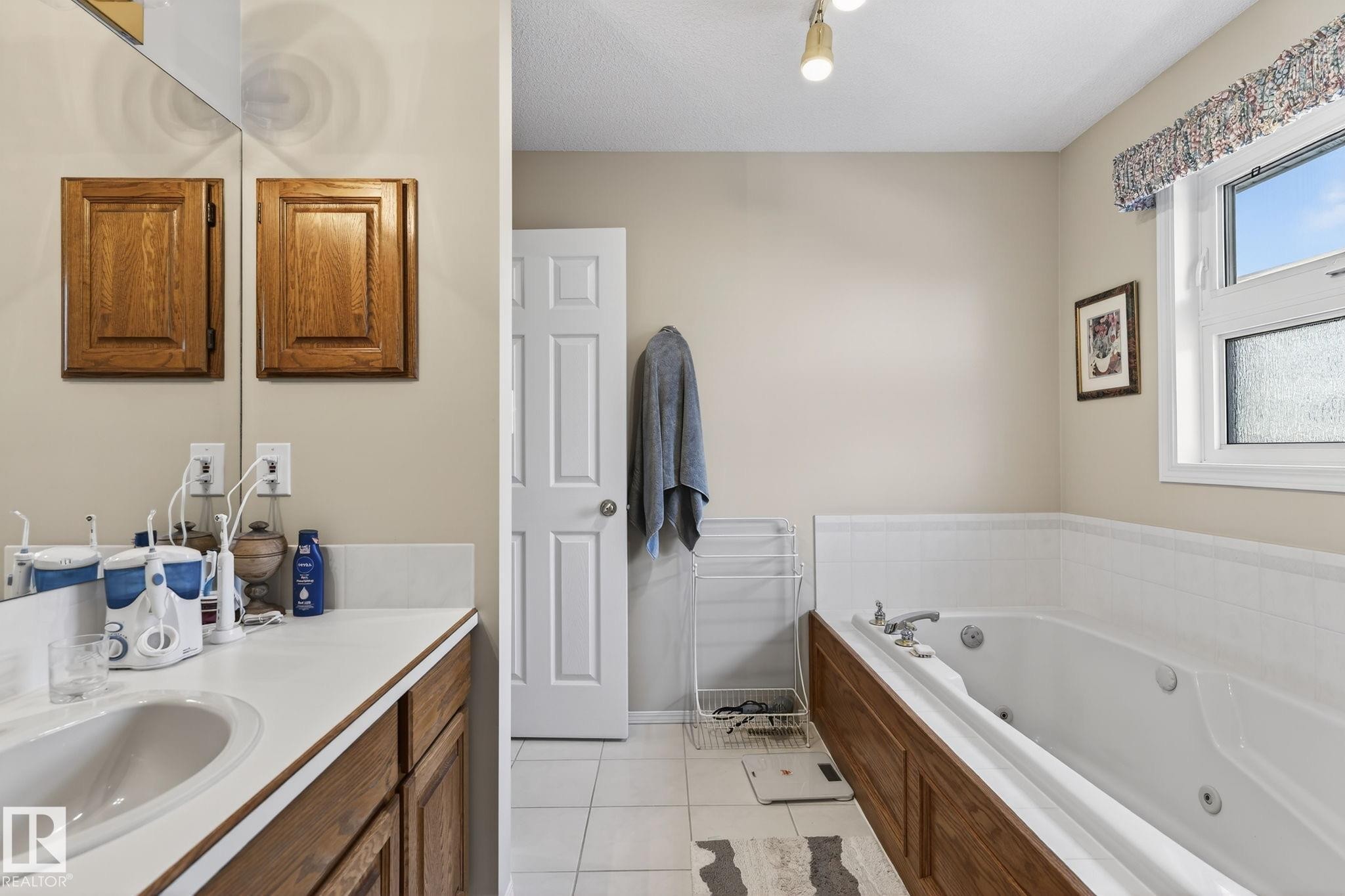 Bathroom with vanity, light tile patterned floors, and a tub with jets - 313 Hedley Way, Edmonton, AB - Indoor Photo Showing Bathroom