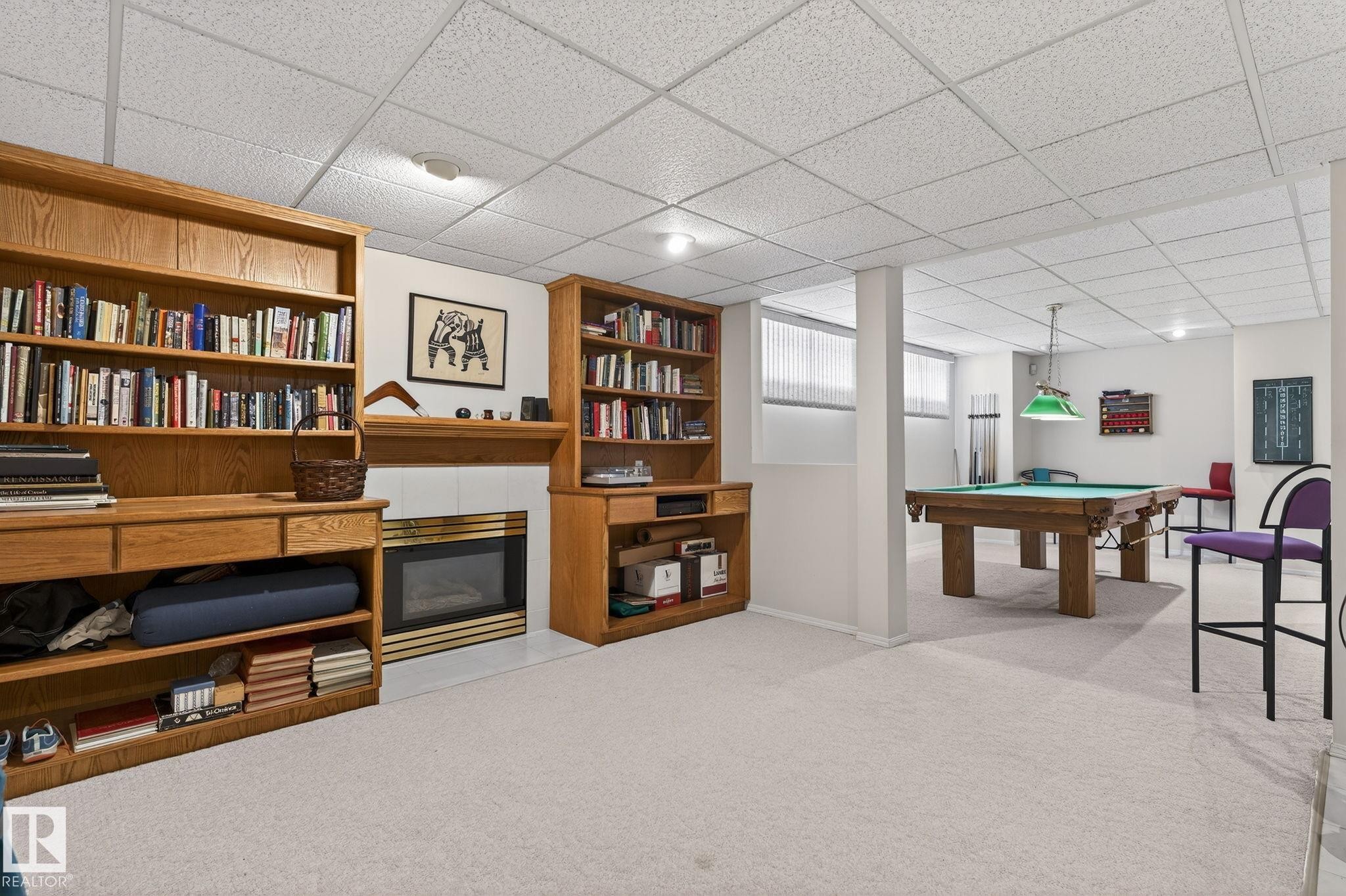 Recreation room with a tile fireplace, light colored carpet, pool table, and a drop ceiling - 313 Hedley Way, Edmonton, AB - Indoor