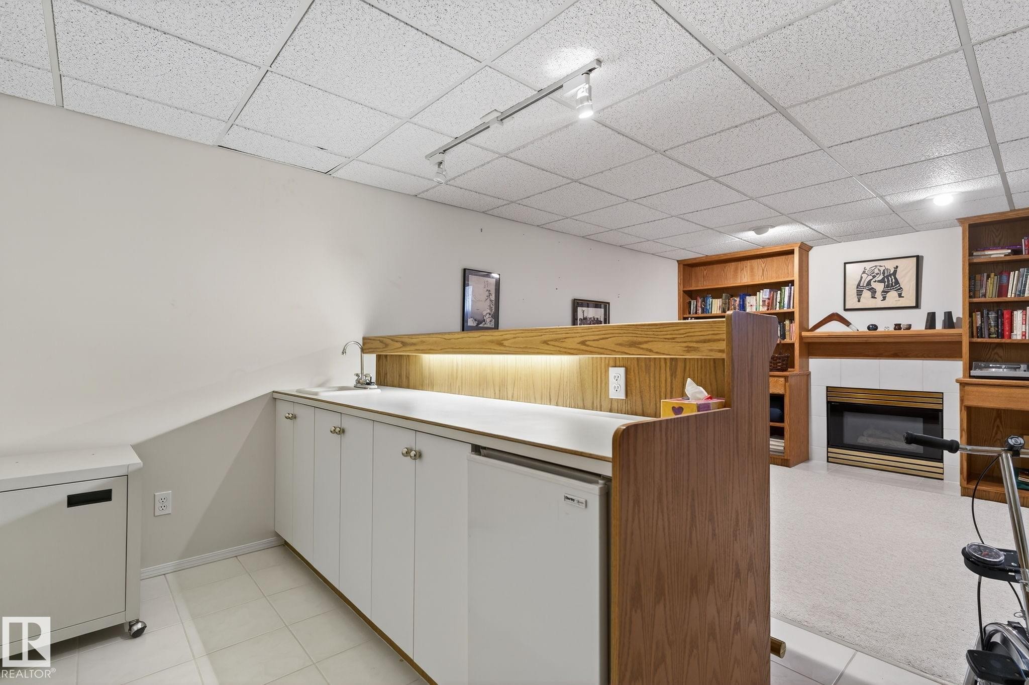 Kitchen with a drop ceiling, white cabinets, a glass covered fireplace, white refrigerator, and light countertops - 313 Hedley Way, Edmonton, AB - Indoor