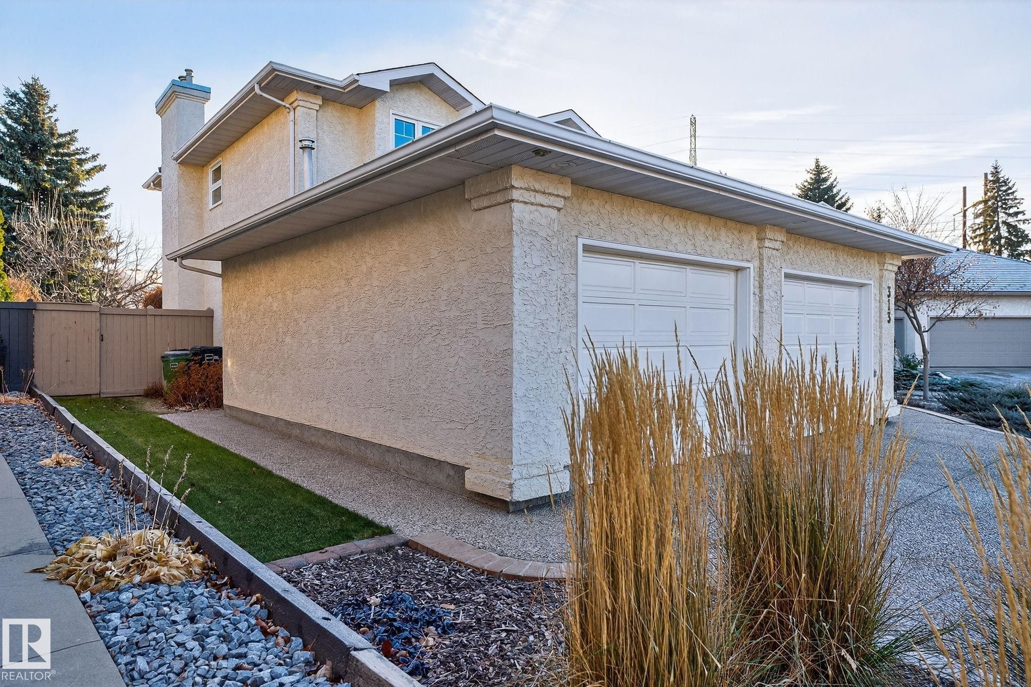 View of side of home featuring stucco siding, a chimney, a gate, and a garage - 313 Hedley Way, Edmonton, AB - Outdoor With Exterior