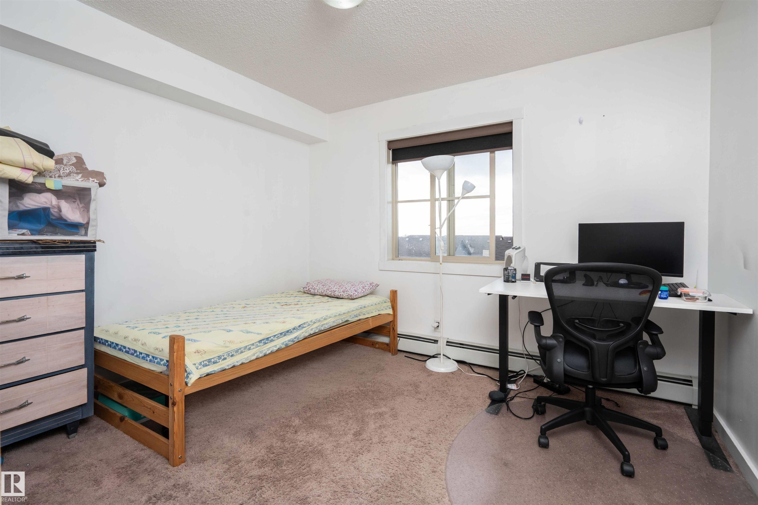 Bedroom with light colored carpet, a desk, a textured ceiling, and a baseboard heating unit - 415 111 Watt Common, Edmonton, AB - Indoor Photo Showing Bedroom