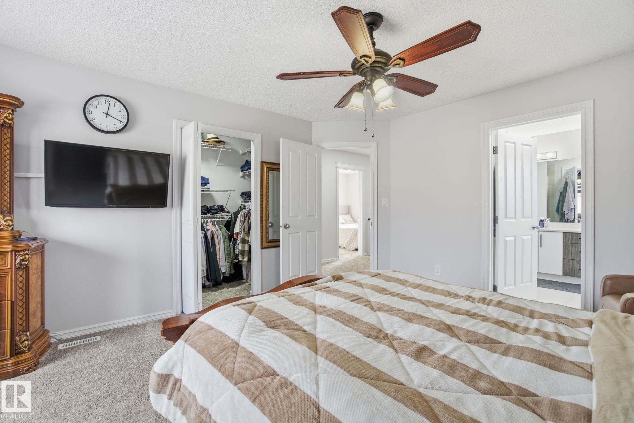 Bedroom featuring a spacious closet, light colored carpet, a textured ceiling, ceiling fan, and ensuite bath - 1532 37C Avenue, Edmonton, AB - Indoor Photo Showing Bedroom