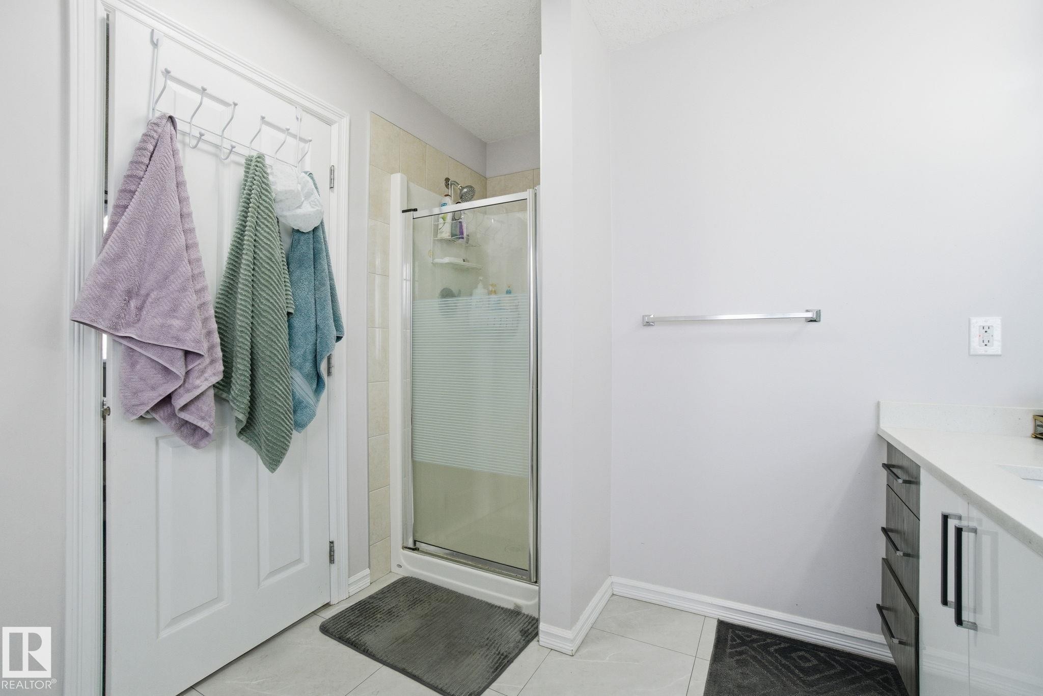 Bathroom featuring a shower stall, vanity, a textured ceiling, and light tile patterned floors - 1532 37C Avenue, Edmonton, AB - Indoor