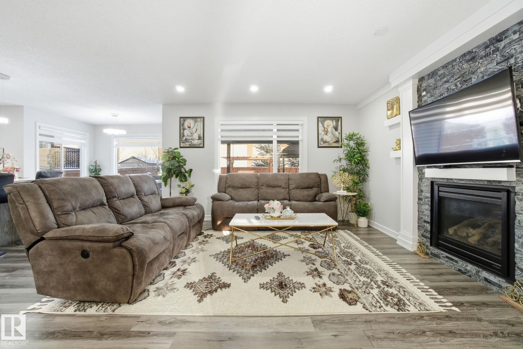 Living room featuring wood finished floors, a stone fireplace, and recessed lighting - 1532 37C Avenue, Edmonton, AB - Indoor Photo Showing Living Room With Fireplace