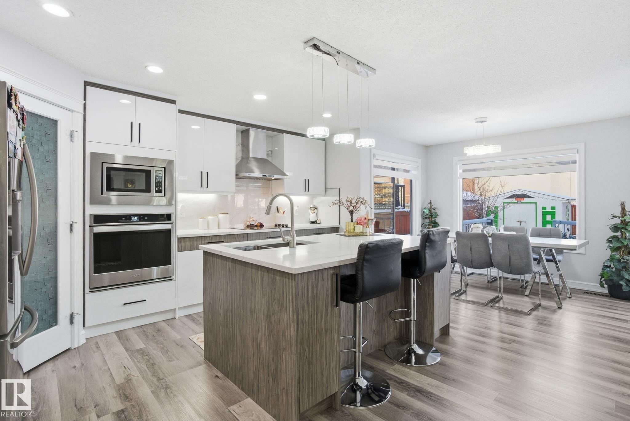 Kitchen with white cabinets, modern cabinets, tasteful backsplash, appliances with stainless steel finishes, and light wood-type flooring - 1532 37C Avenue, Edmonton, AB - Indoor Photo Showing Kitchen With Upgraded Kitchen