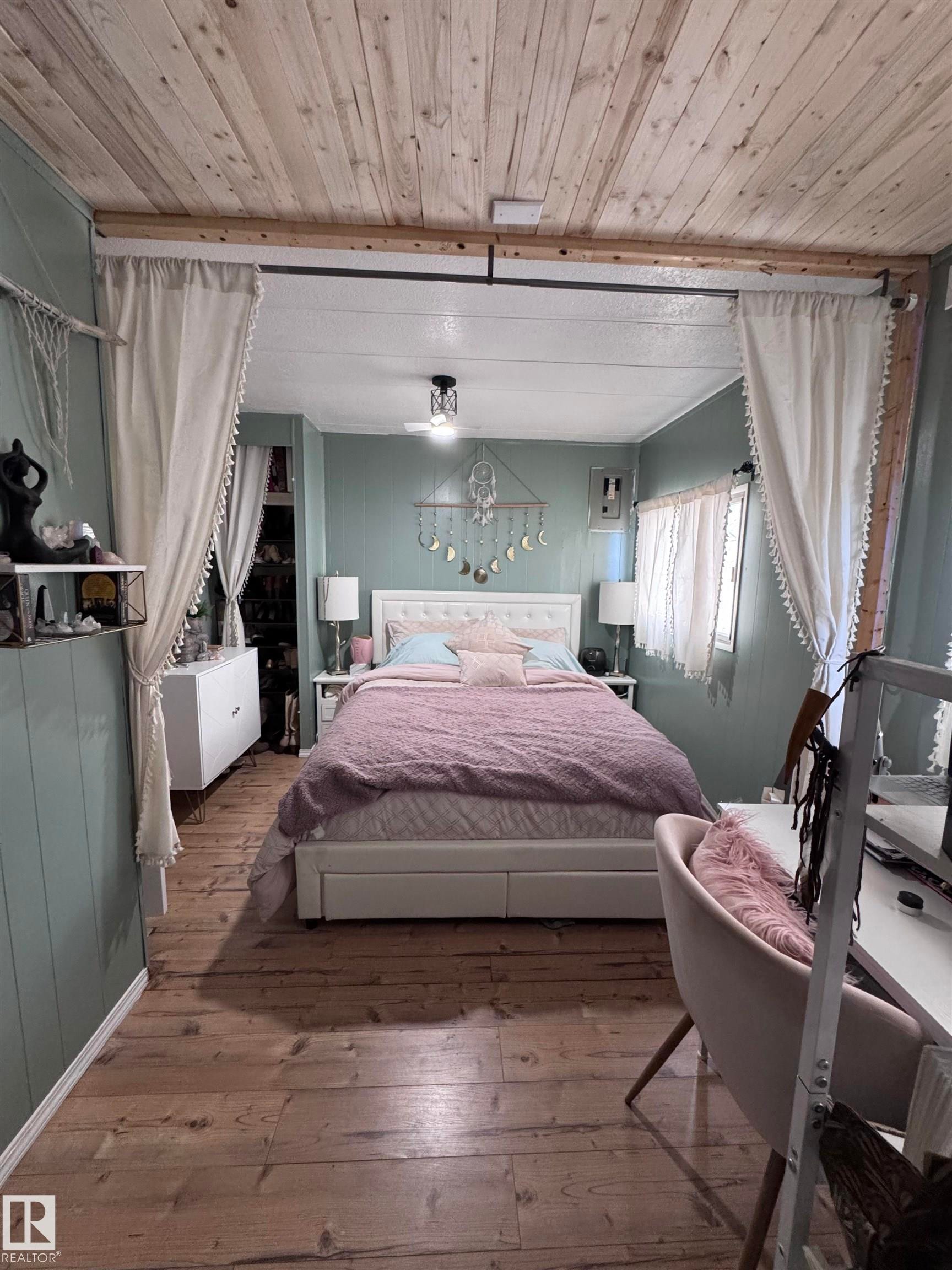 Bedroom featuring hardwood / wood-style flooring, wood ceiling, and wooden walls - #44 9501 104 Ave, Westlock, AB - Indoor Photo Showing Bedroom