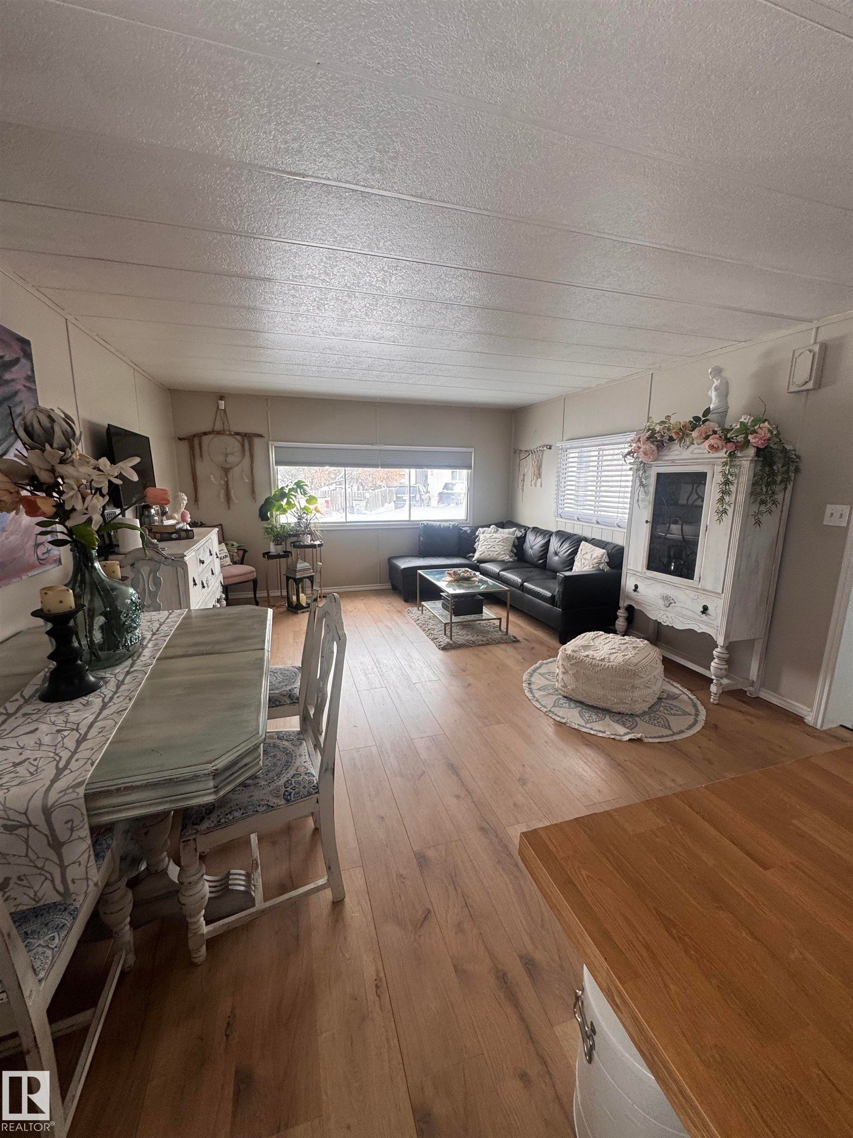 Dining room with hardwood / wood-style floors and a textured ceiling - #44 9501 104 Ave, Westlock, AB - Indoor With Fireplace