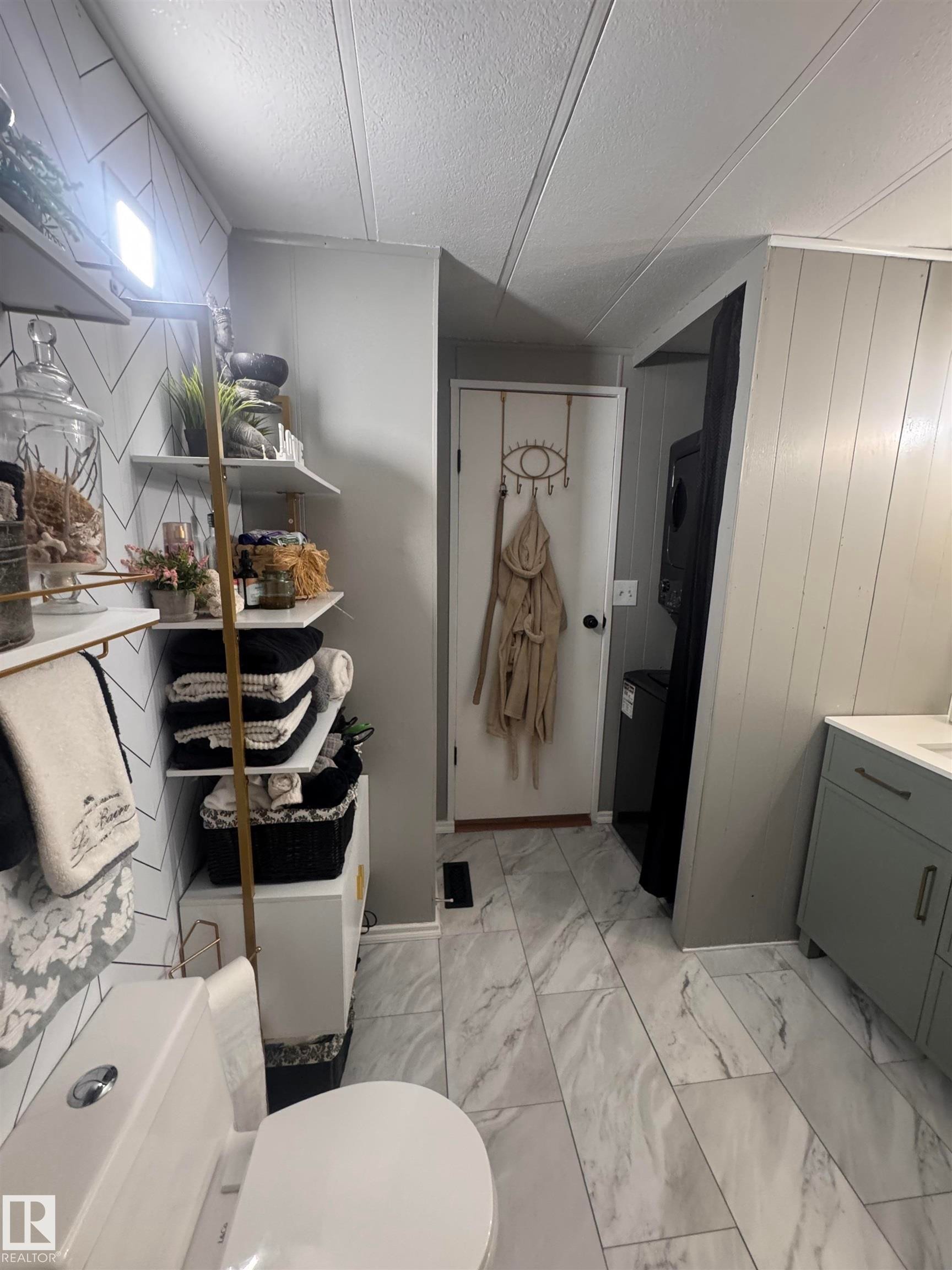 Bathroom with light marble finish flooring, wooden walls, a textured ceiling, and vanity - #44 9501 104 Ave, Westlock, AB - Indoor