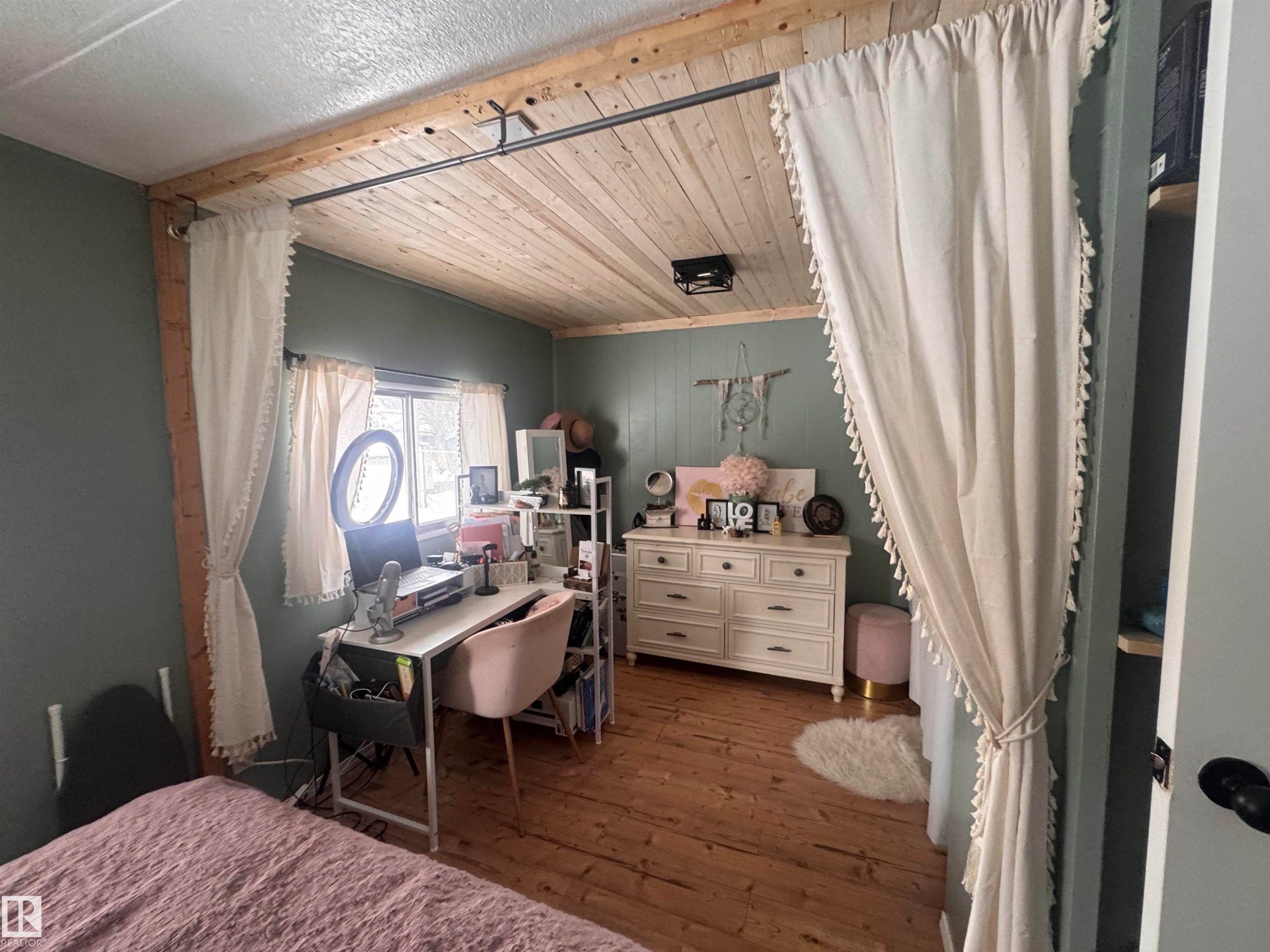 Bedroom with dark wood-style flooring, wooden ceiling, and wooden walls - #44 9501 104 Ave, Westlock, AB - Indoor