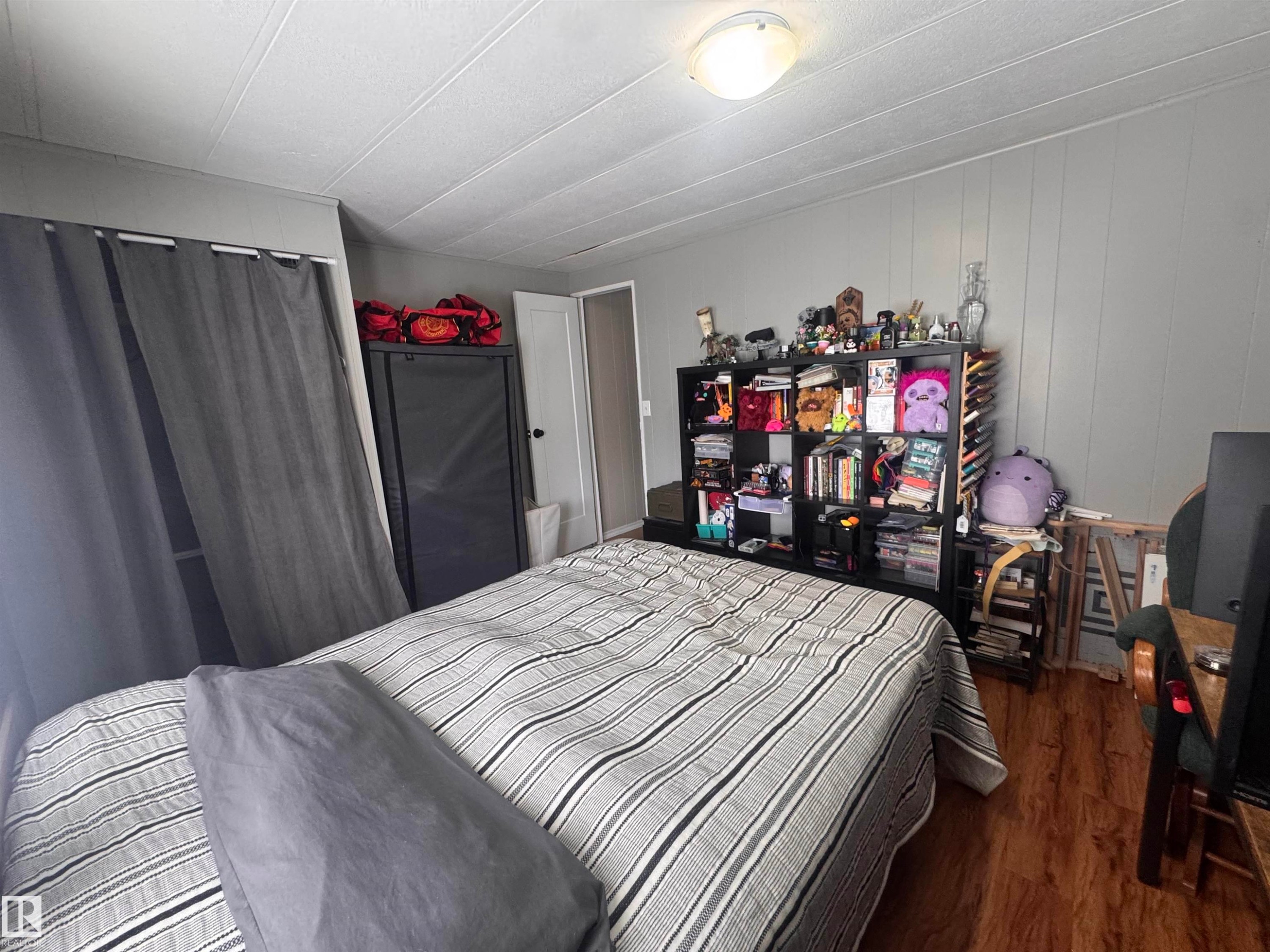 Bedroom with dark wood finished floors and wood walls - #44 9501 104 Ave, Westlock, AB - Indoor Photo Showing Bedroom