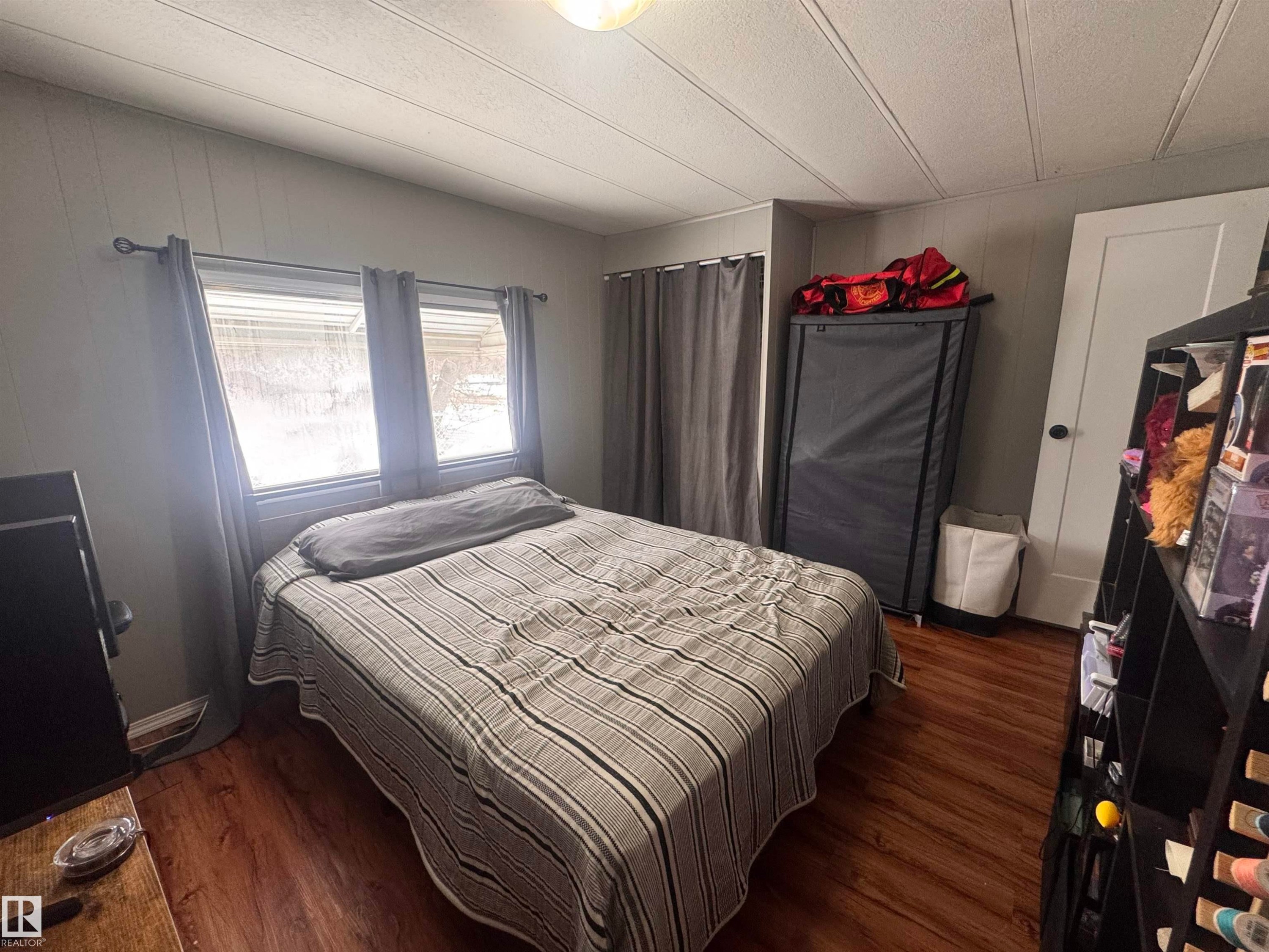 Bedroom featuring dark wood-type flooring - #44 9501 104 Ave, Westlock, AB - Indoor Photo Showing Bedroom