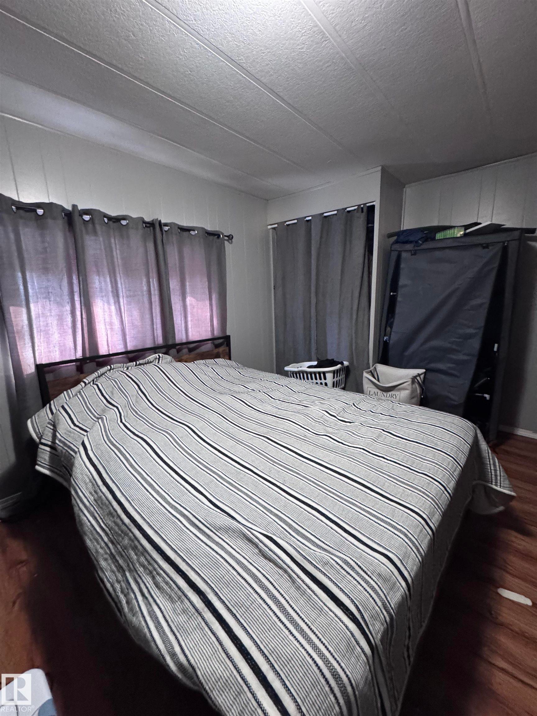 Bedroom with dark wood finished floors and a textured ceiling - #44 9501 104 Ave, Westlock, AB - Indoor Photo Showing Bedroom