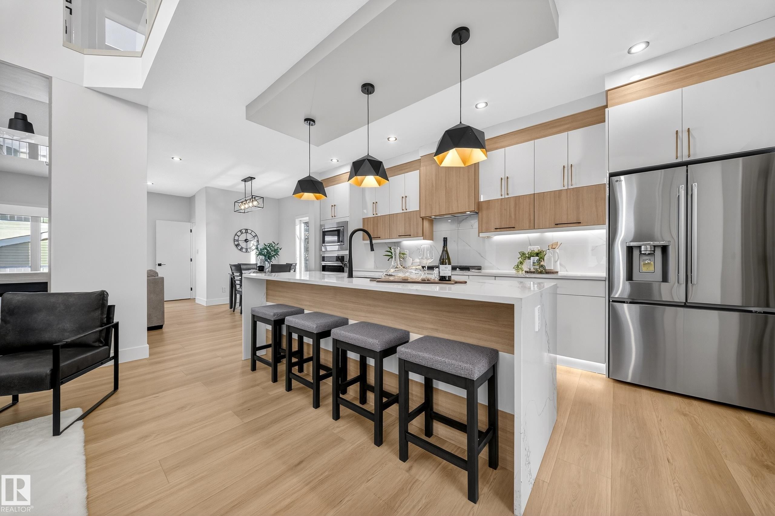 Kitchen featuring stainless steel appliances, decorative light fixtures, a kitchen breakfast bar, and an island with sink - 9907 68 Street, Edmonton, AB - Indoor Photo Showing Kitchen With Upgraded Kitchen