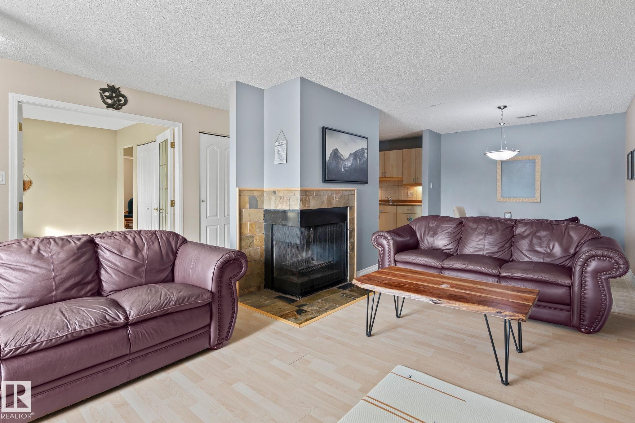Living area featuring light wood-style floors, a tile fireplace, and a textured ceiling - 1925 Saddleback Road, Edmonton, AB - Indoor Photo Showing Living Room With Fireplace