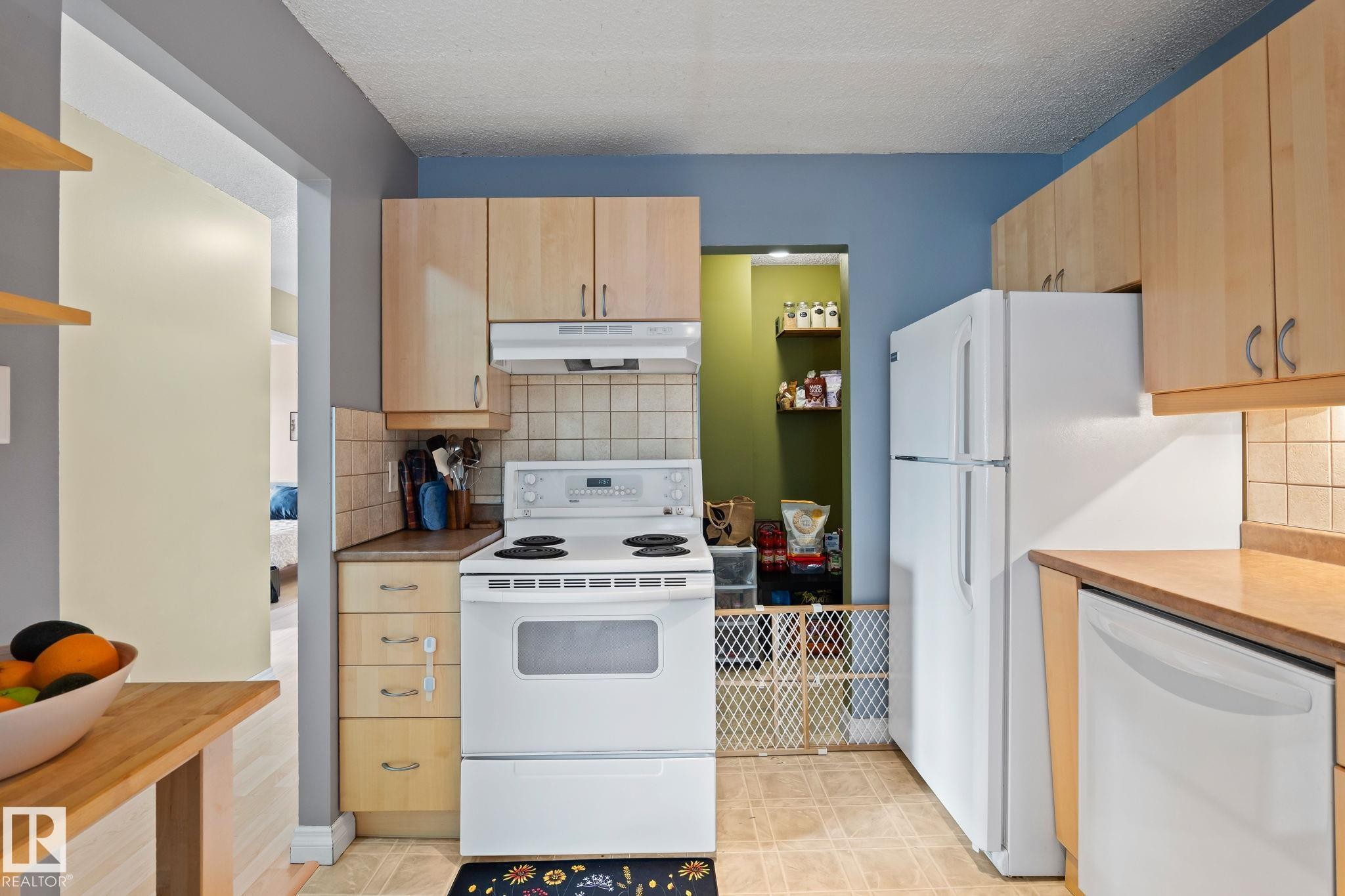 Kitchen featuring white appliances, light wood finish cabinetry, tasteful backsplash, a textured ceiling, and light countertops - 1925 Saddleback Road, Edmonton, AB - Indoor Photo Showing Kitchen