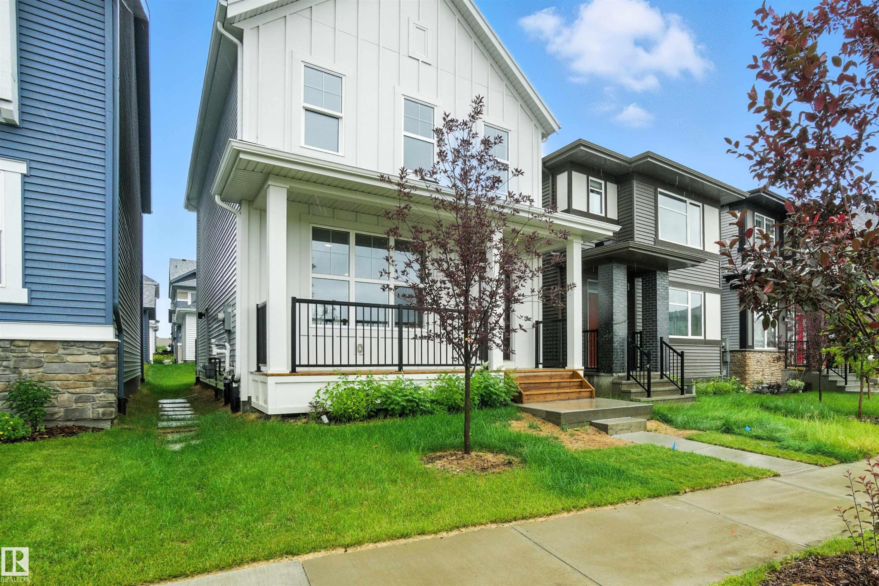 View of front facade featuring a front yard and board and batten siding - 20727 25 Ave, Edmonton, AB - Outdoor With Facade