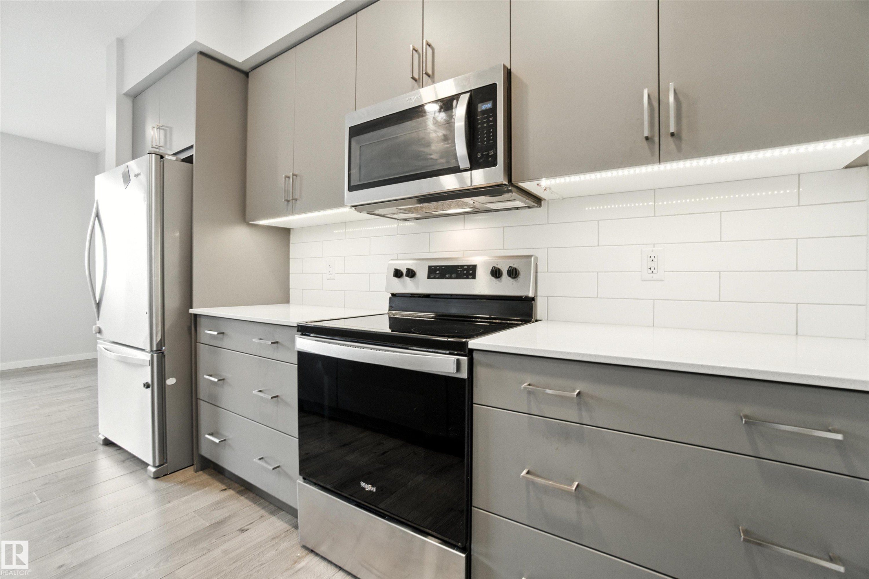Kitchen featuring gray cabinets, stainless steel appliances, decorative backsplash, and light wood finished floors - 20727 25 Ave, Edmonton, AB - Indoor Photo Showing Kitchen With Upgraded Kitchen