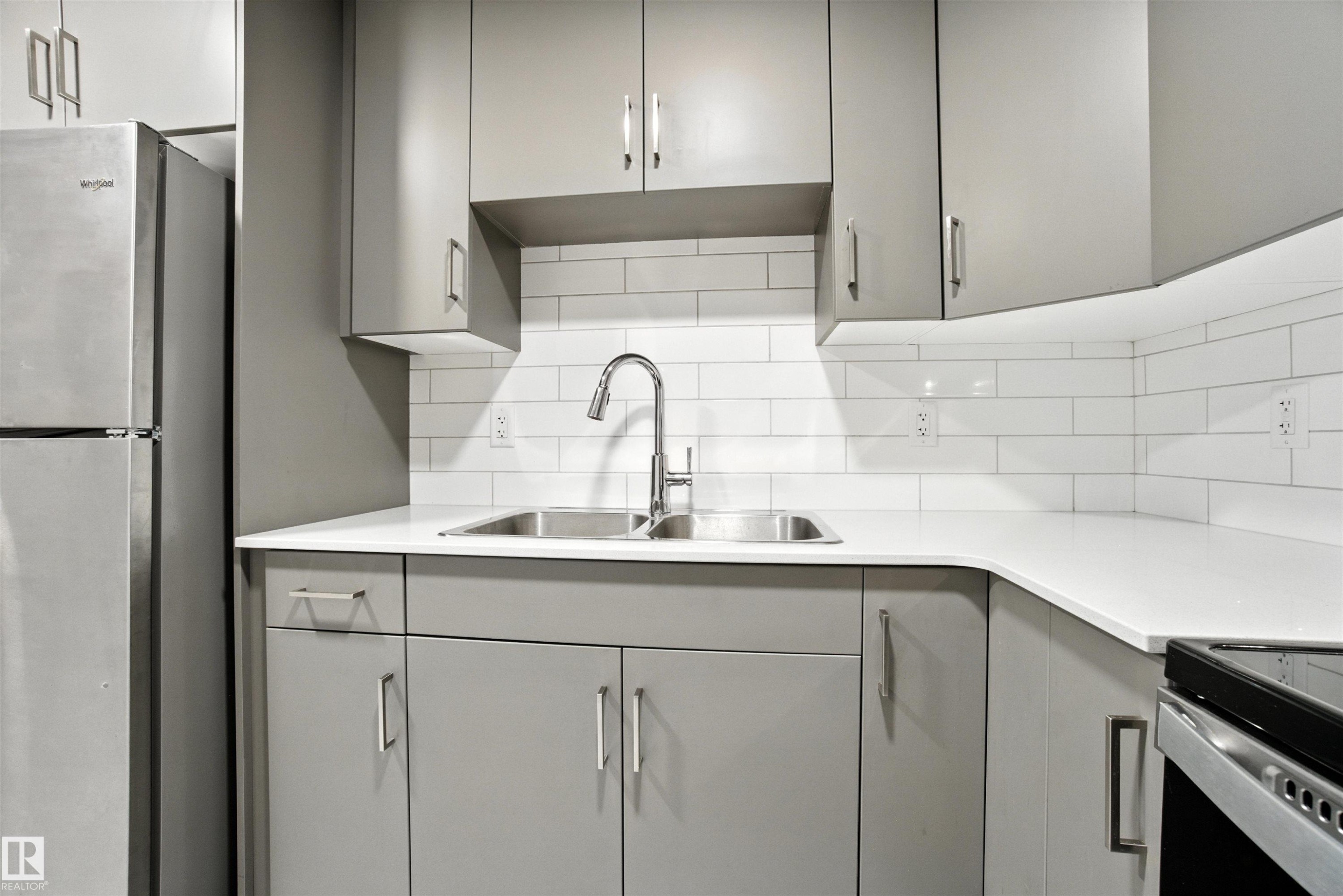 Kitchen featuring gray cabinetry, freestanding refrigerator, and backsplash - 20727 25 Ave, Edmonton, AB - Indoor Photo Showing Kitchen With Double Sink