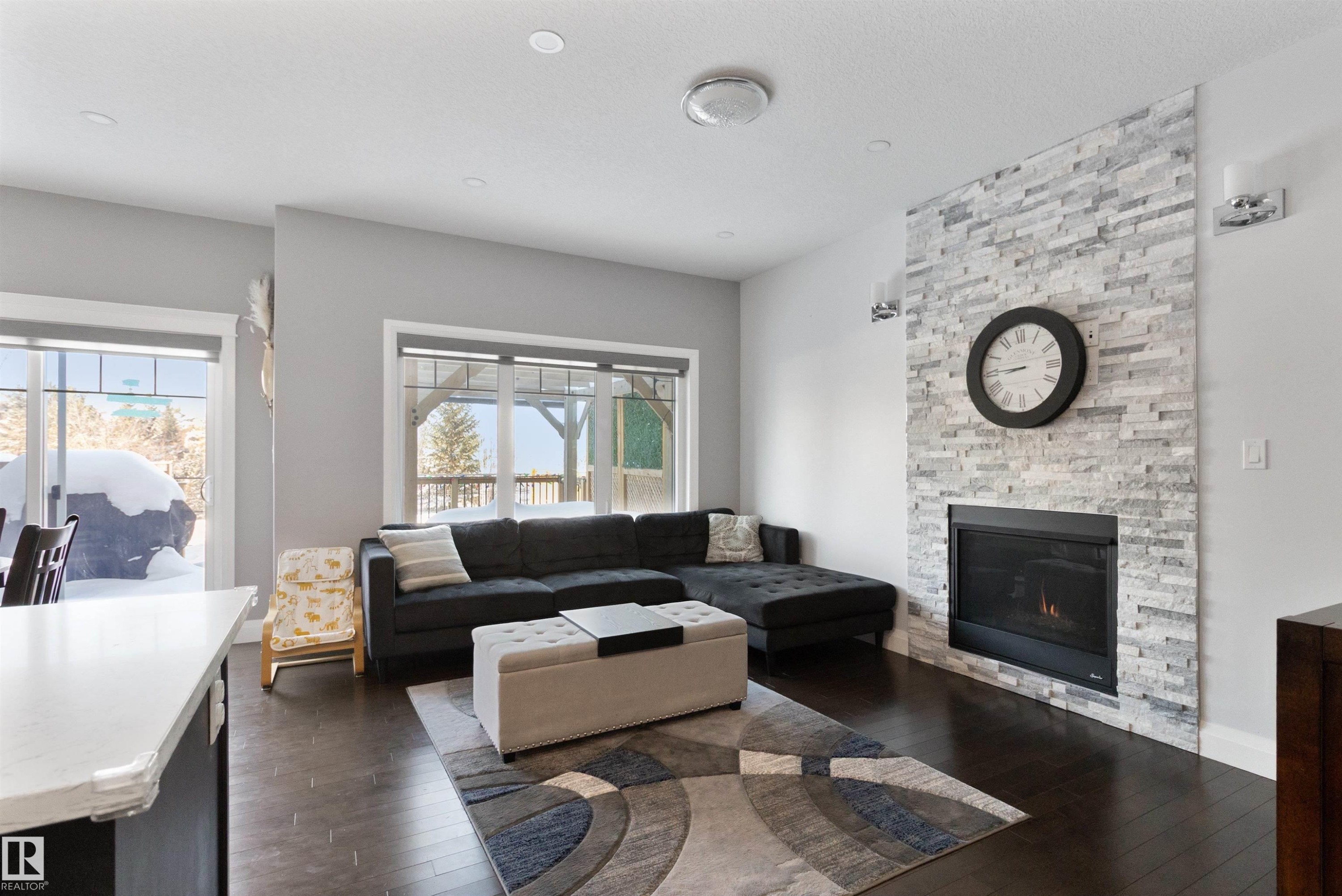 Living room featuring dark wood-style floors and a stone fireplace - 56 Durrand Bend, Fort Saskatchewan, AB - Indoor Photo Showing Living Room With Fireplace