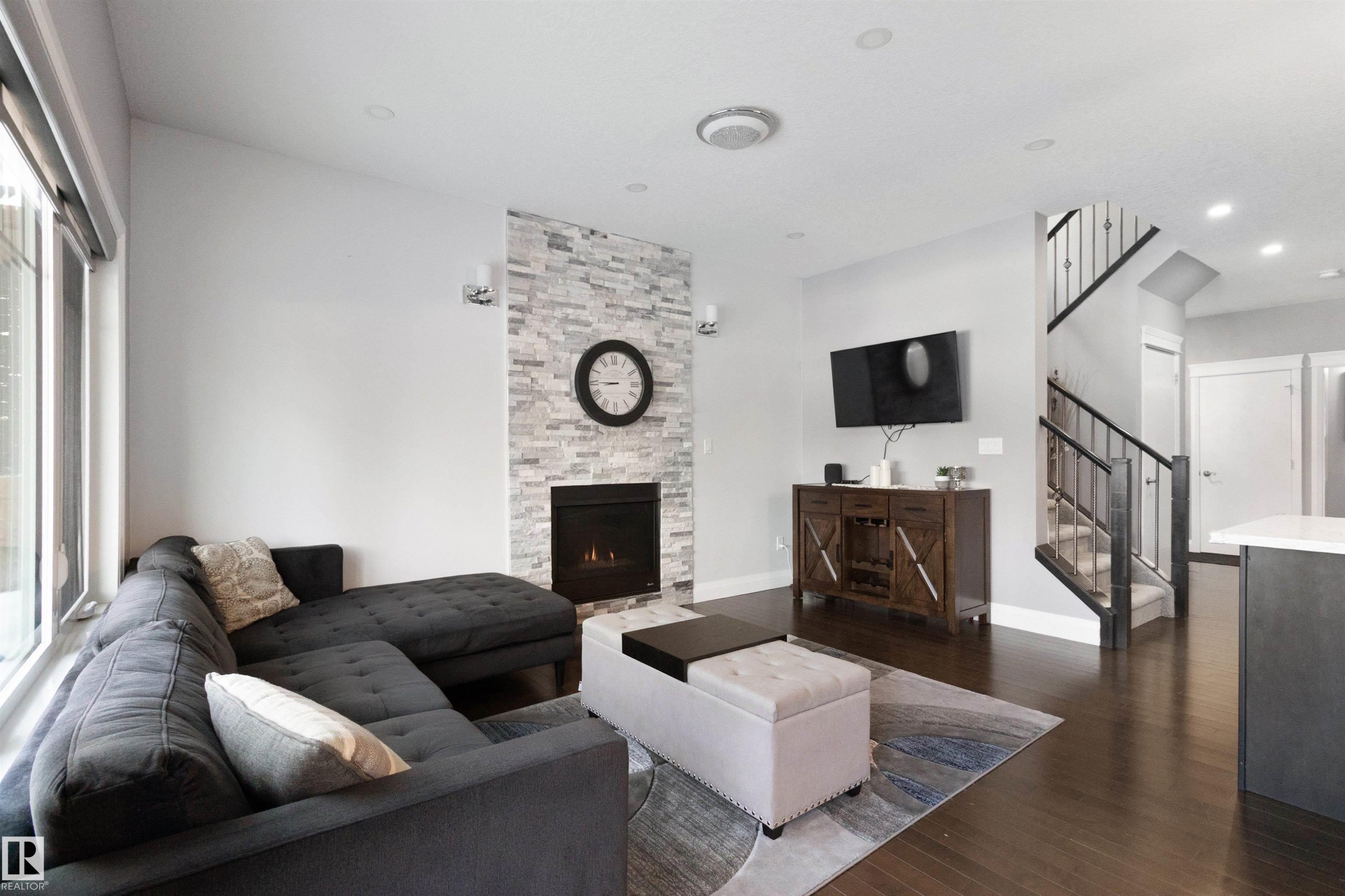Living room featuring a stone fireplace, dark wood-type flooring, and recessed lighting - 56 Durrand Bend, Fort Saskatchewan, AB - Indoor Photo Showing Living Room With Fireplace