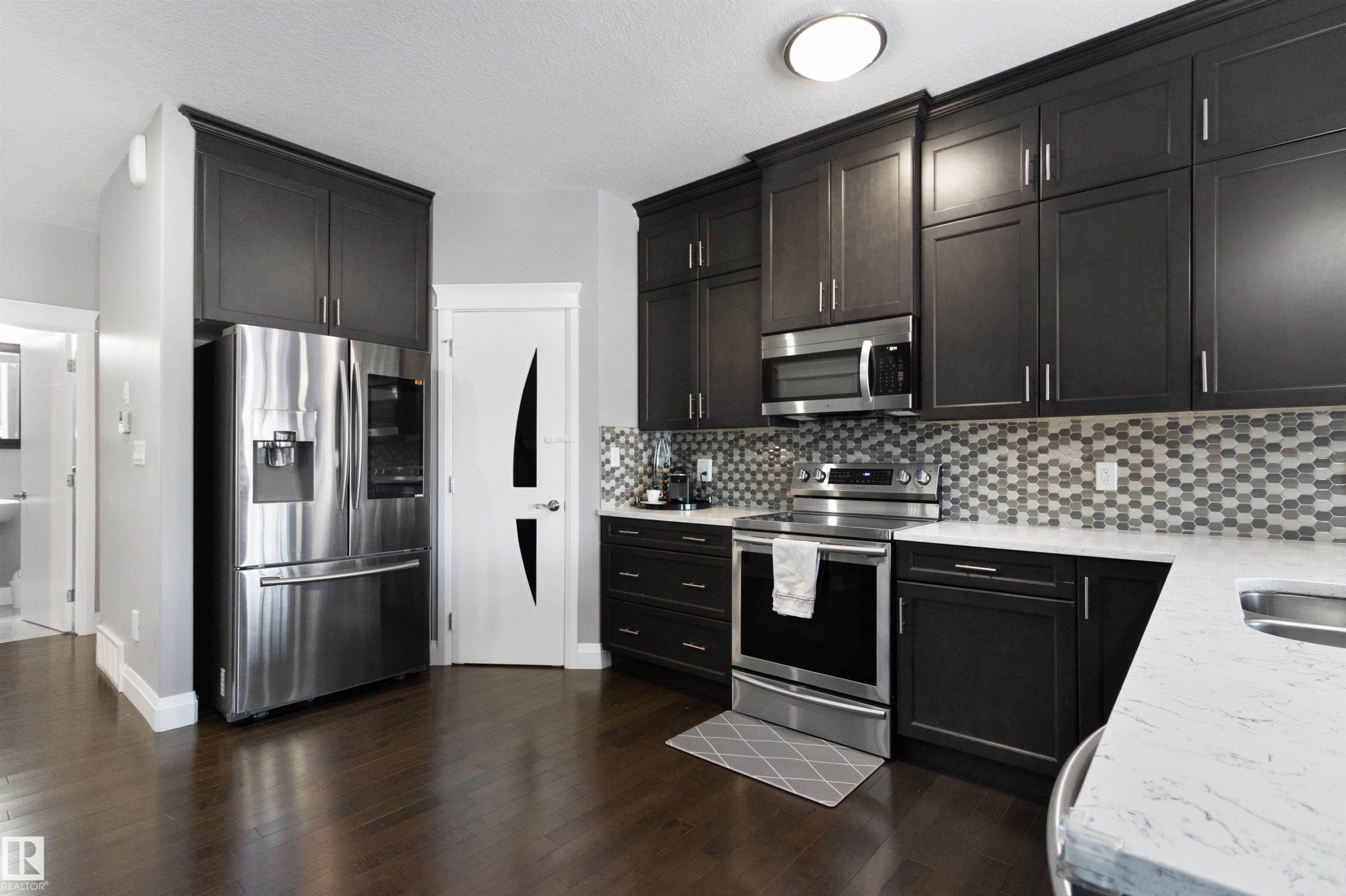 Kitchen featuring stainless steel appliances, light stone countertops, dark wood finished floors, and decorative backsplash - 56 Durrand Bend, Fort Saskatchewan, AB - Indoor Photo Showing Kitchen With Double Sink With Upgraded Kitchen