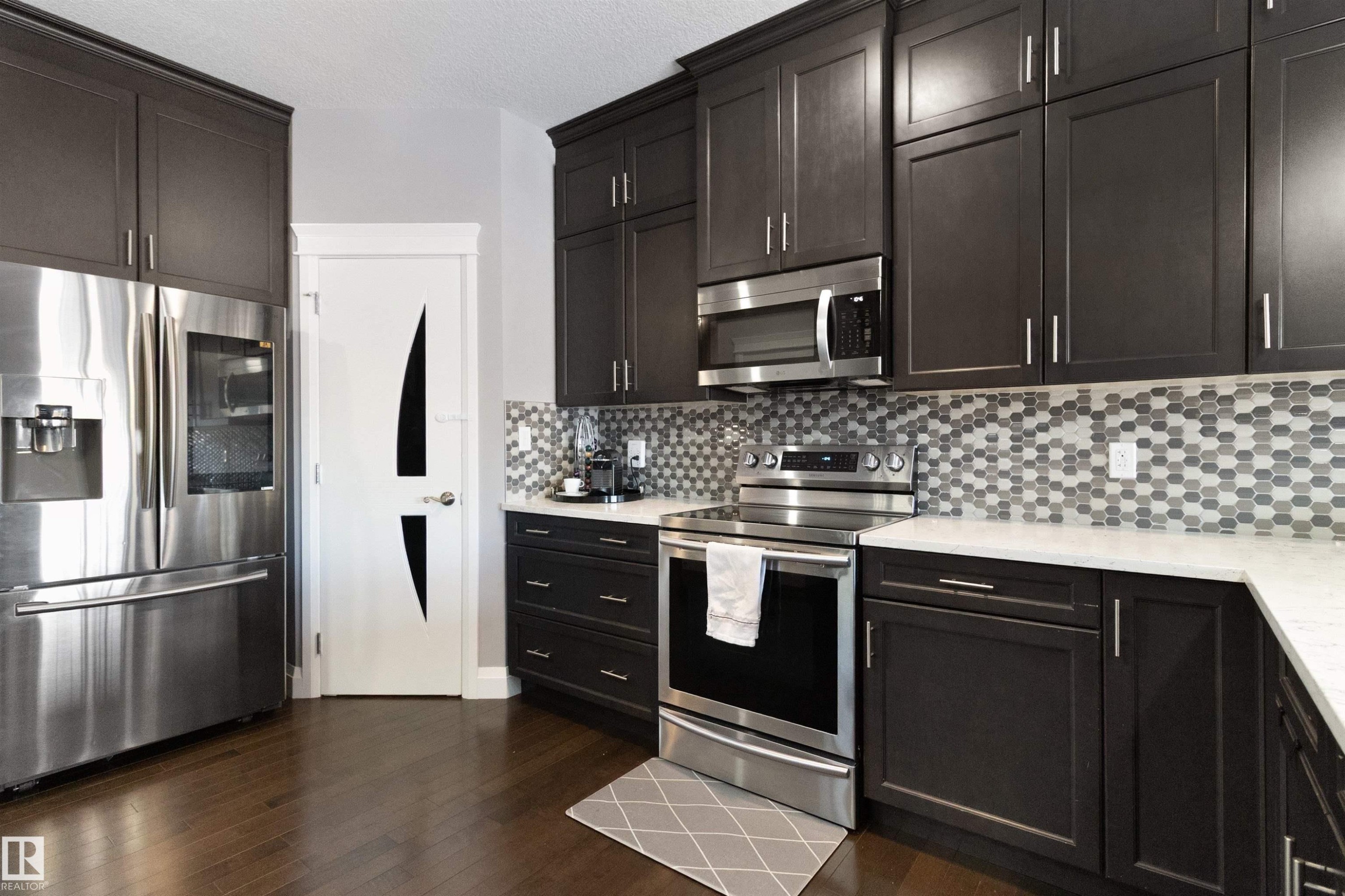 Kitchen featuring stainless steel appliances, light stone countertops, dark wood-style floors, and dark wood finish cabinetry - 56 Durrand Bend, Fort Saskatchewan, AB - Indoor Photo Showing Kitchen With Upgraded Kitchen