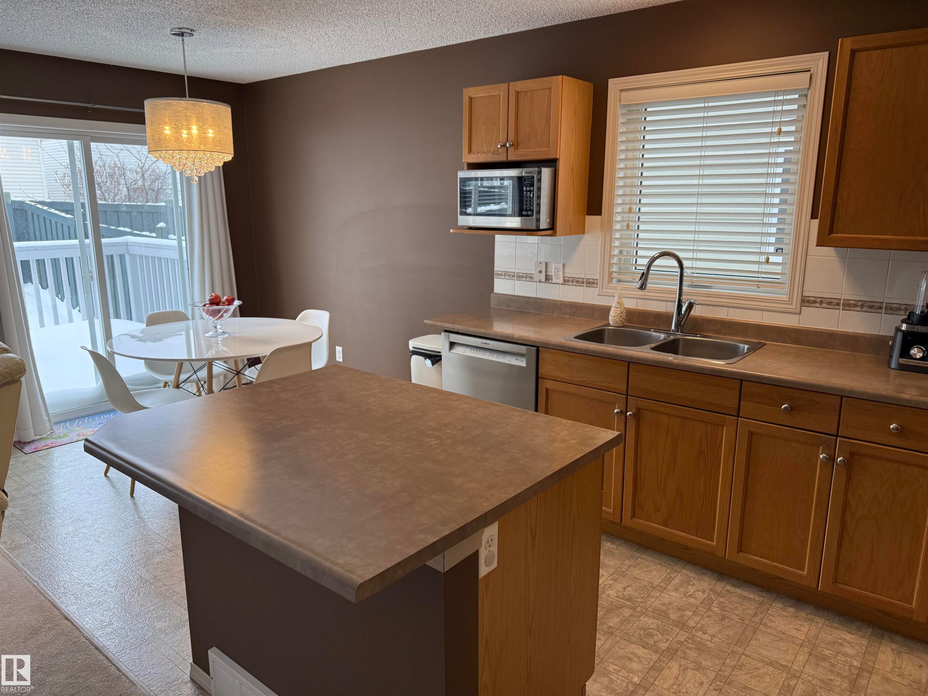 Kitchen featuring tasteful backsplash, light floors, dark countertops, wood finish cabinetry, and stainless steel appliances - 19 2021 Grantham Crest, Edmonton, AB - Indoor Photo Showing Kitchen With Double Sink