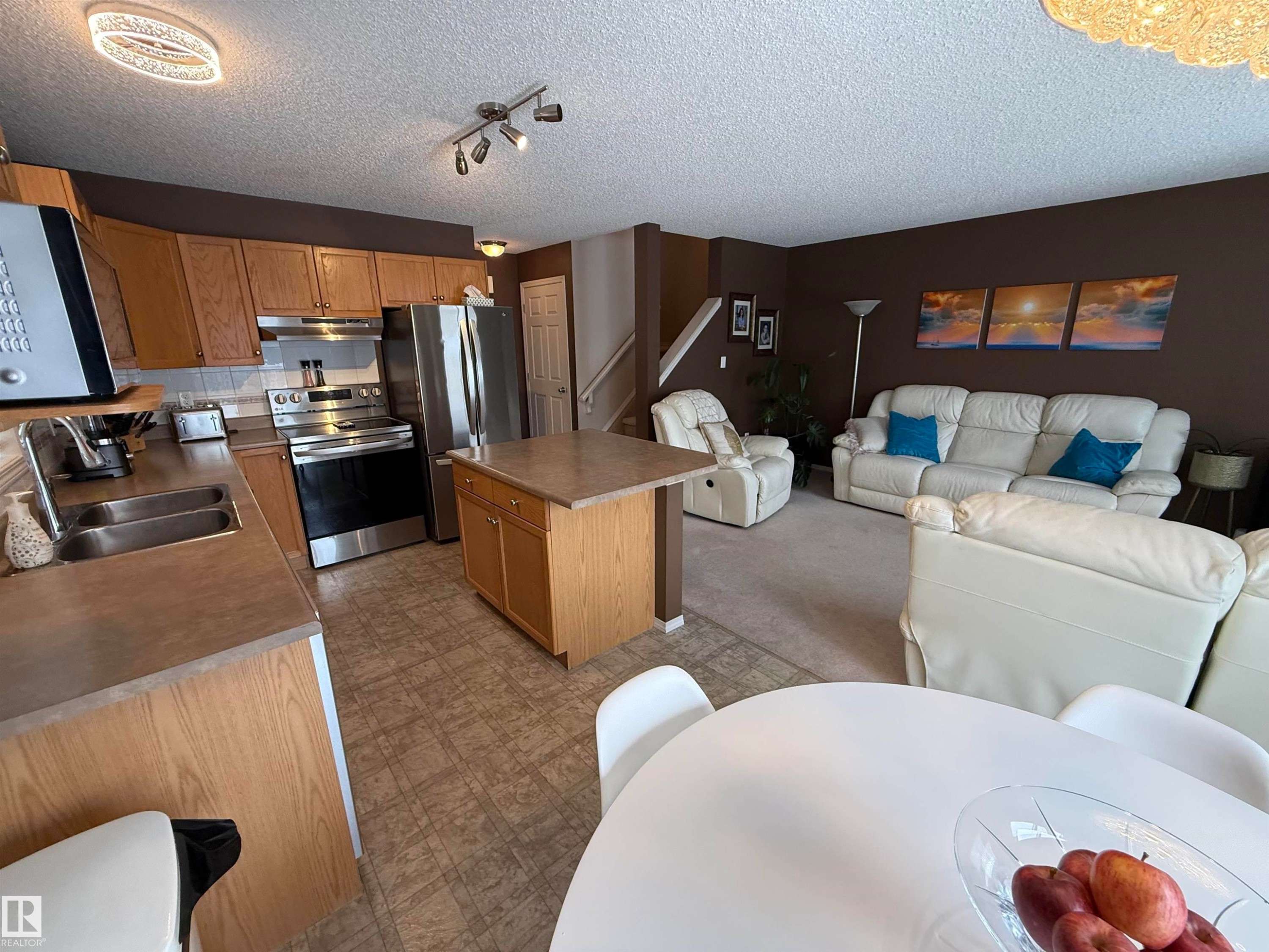 Kitchen featuring stainless steel appliances, a kitchen island, tile patterned floors, open floor plan, and wood finish cabinetry - 19 2021 Grantham Crest, Edmonton, AB - Indoor Photo Showing Kitchen With Stainless Steel Kitchen With Double Sink