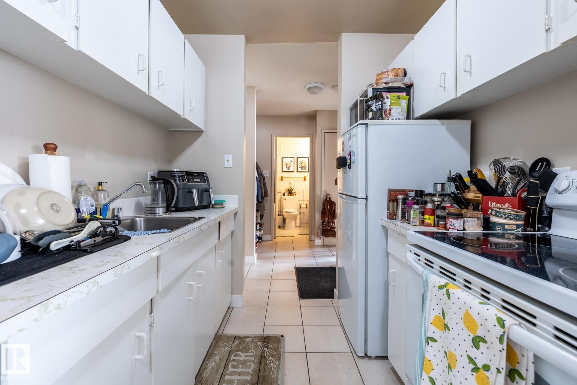 Kitchen with white appliances, white cabinets, and light countertops - 15 10620 122 Street, Edmonton, AB - Indoor Photo Showing Kitchen