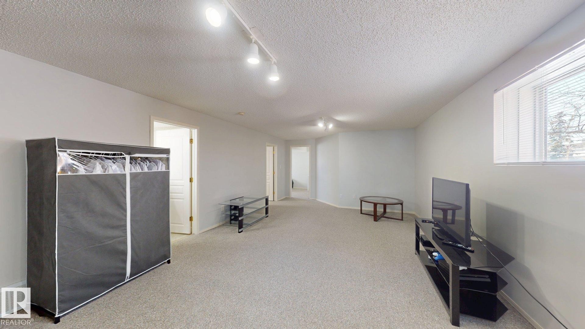 Unfurnished room with rail lighting, a textured ceiling, and light carpet - 17010 84 Street, Edmonton, AB - Indoor