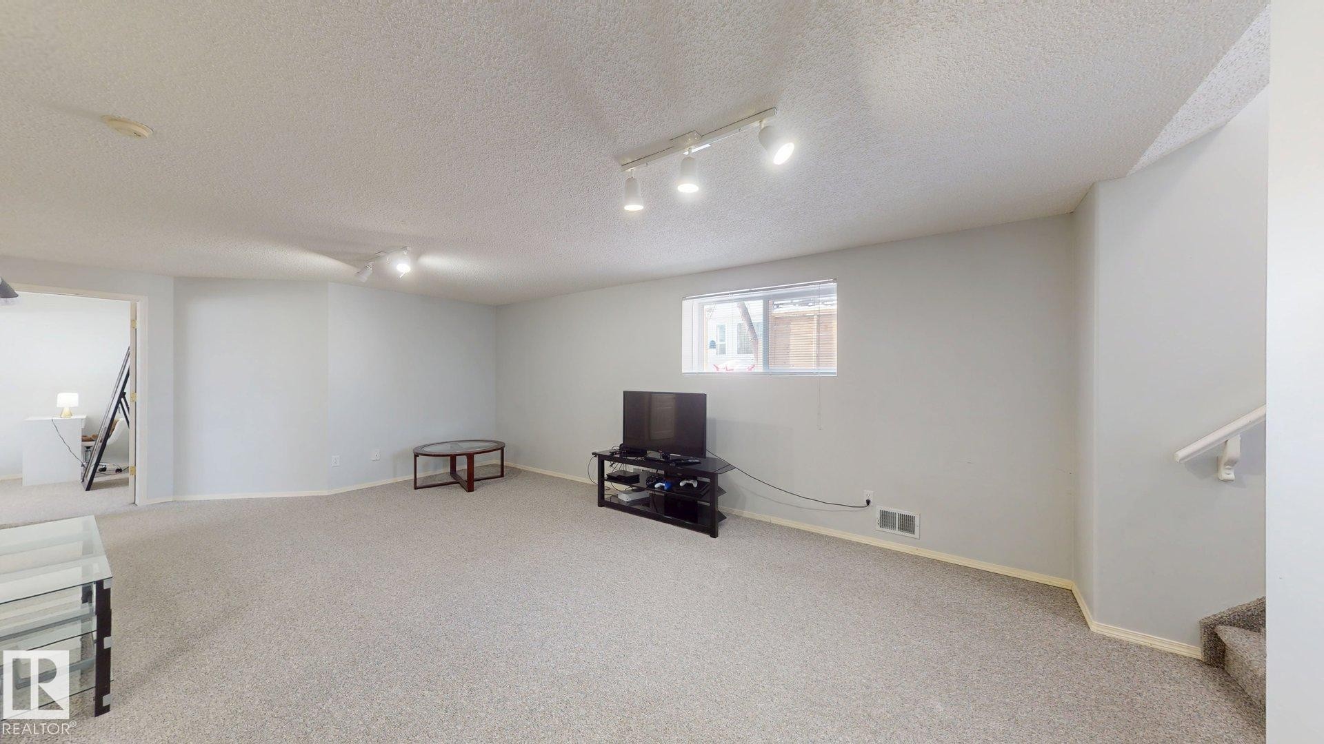 Unfurnished room featuring carpet, track lighting, and a textured ceiling - 17010 84 Street, Edmonton, AB - Indoor