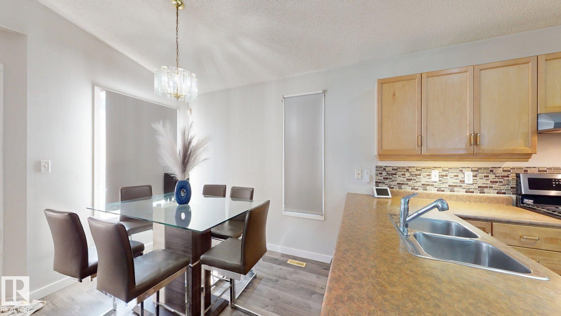 Dining space featuring a textured ceiling, light wood-style flooring, and hanging lights - 17010 84 Street, Edmonton, AB - Indoor