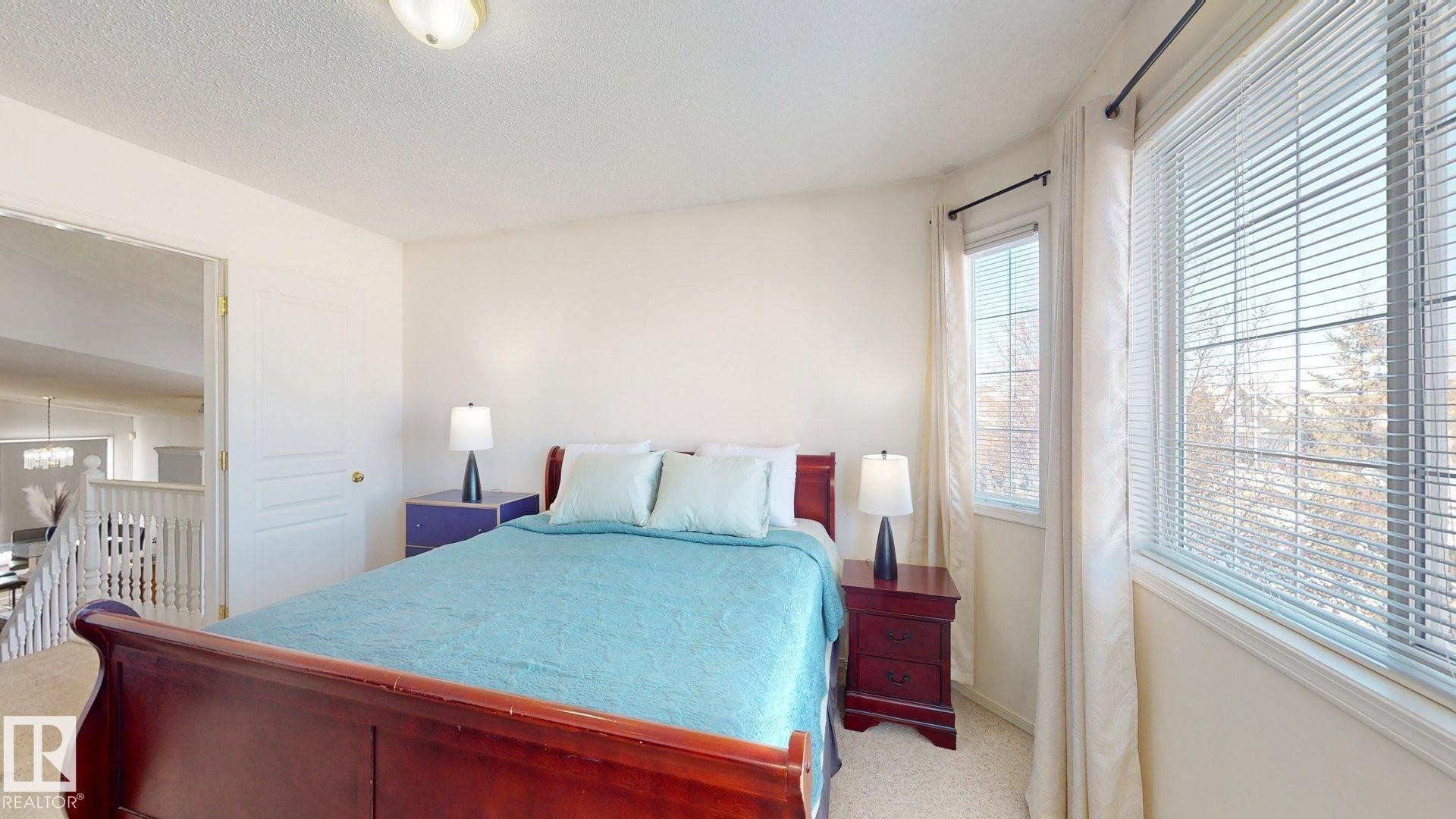 Carpeted bedroom with a textured ceiling and suspended lighting - 17010 84 Street, Edmonton, AB - Indoor Photo Showing Bedroom
