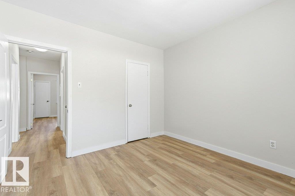 Unfurnished bedroom with light wood-style floors and baseboards - 10704 96 St Nw, Edmonton, AB - Indoor Photo Showing Other Room