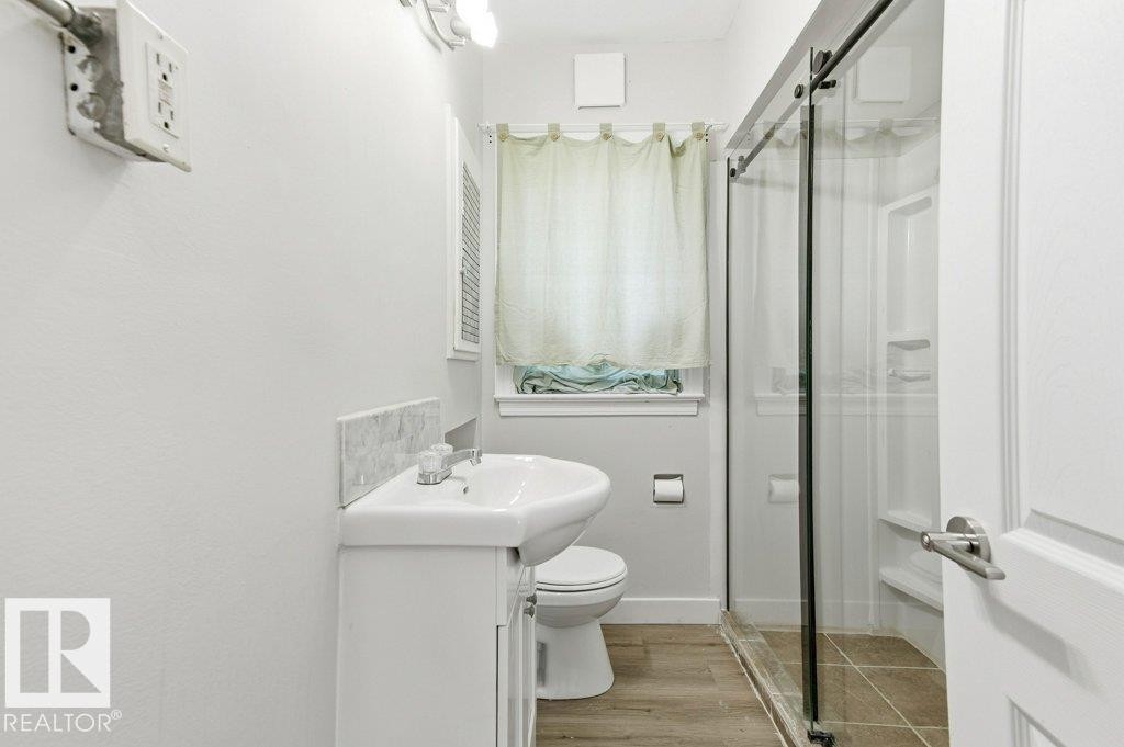 Full bathroom featuring a shower stall, light wood-type flooring, and vanity - 10704 96 St Nw, Edmonton, AB - Indoor Photo Showing Bathroom