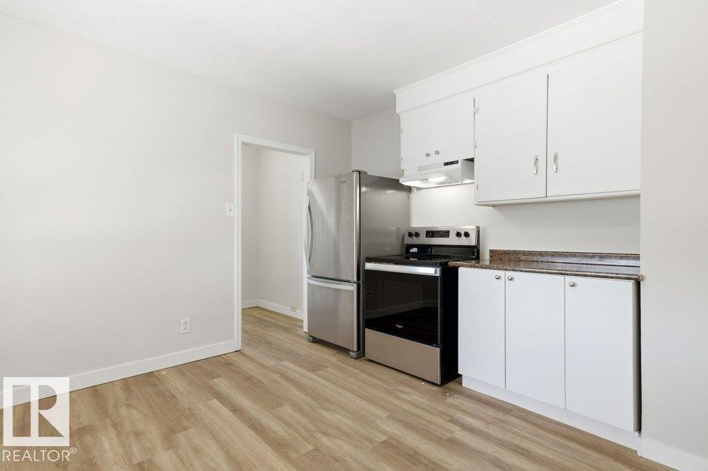 Kitchen with electric stove, white cabinetry, and light wood-style floors - 10704 96 St Nw, Edmonton, AB - Indoor Photo Showing Kitchen