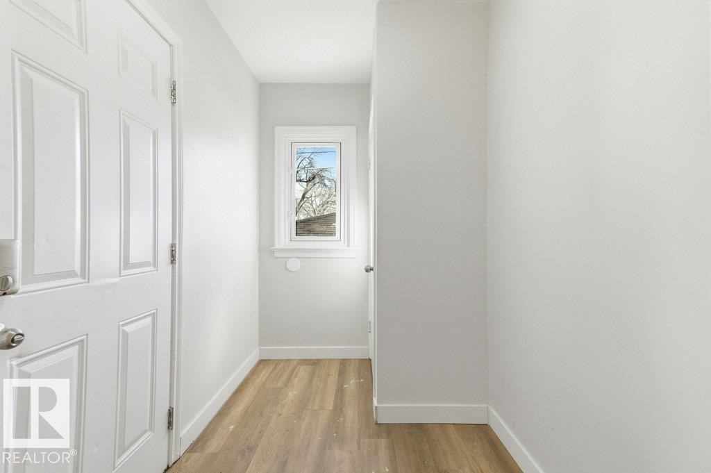 Corridor featuring baseboards and light wood-style flooring - 10704 96 St Nw, Edmonton, AB - Indoor Photo Showing Other Room