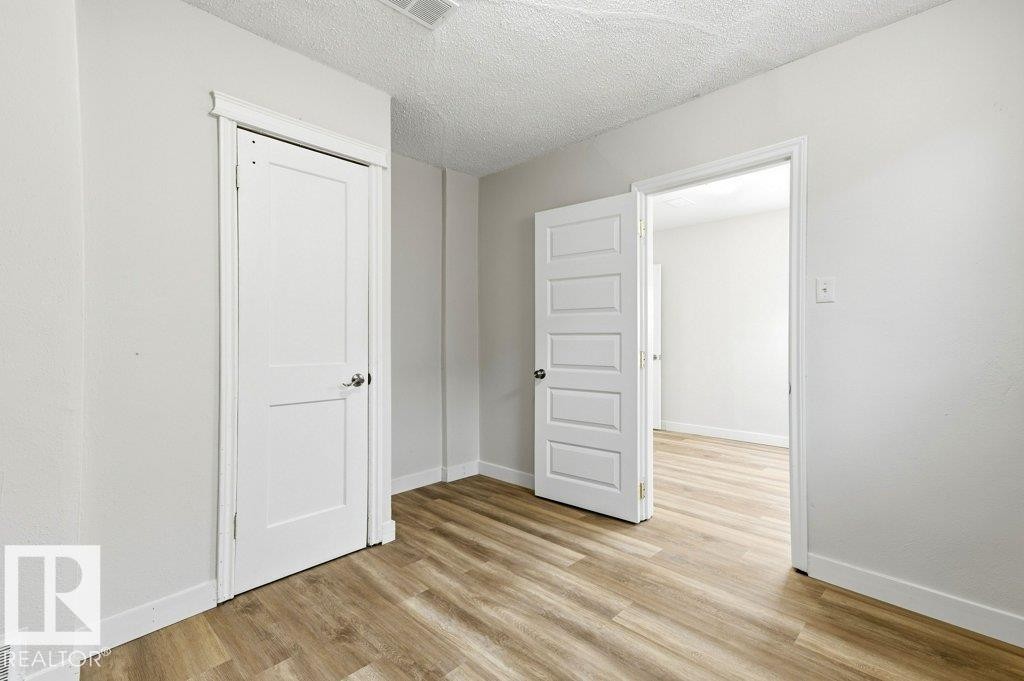 Unfurnished bedroom featuring a textured ceiling and light wood-style flooring - 10704 96 St Nw, Edmonton, AB - Indoor Photo Showing Other Room