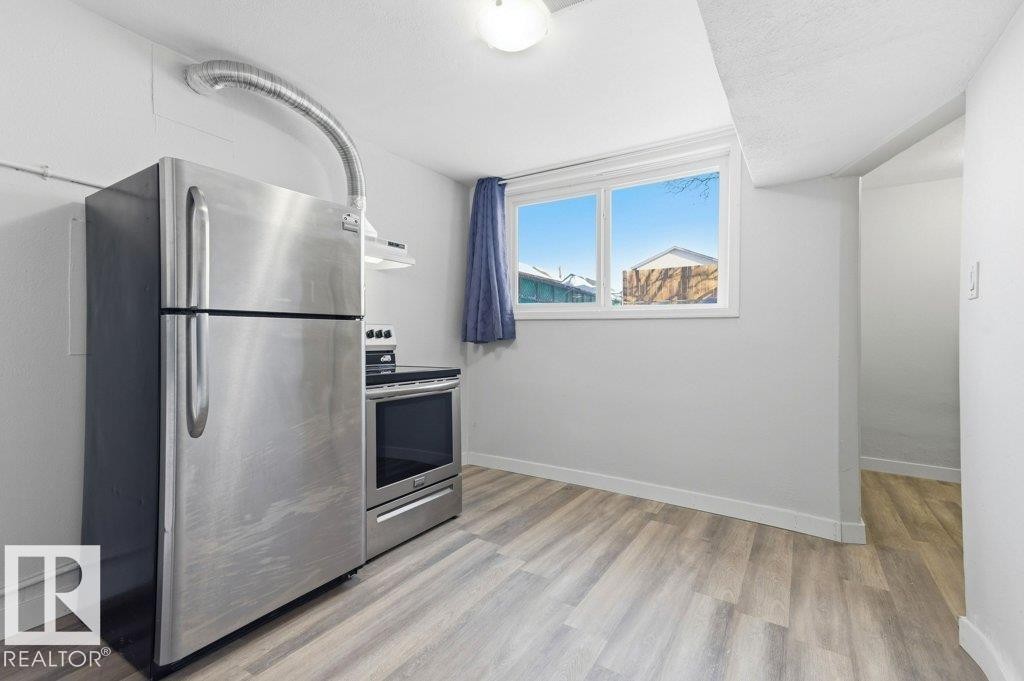Kitchen with stainless steel appliances and light wood-style flooring - 10704 96 St Nw, Edmonton, AB - Indoor Photo Showing Kitchen