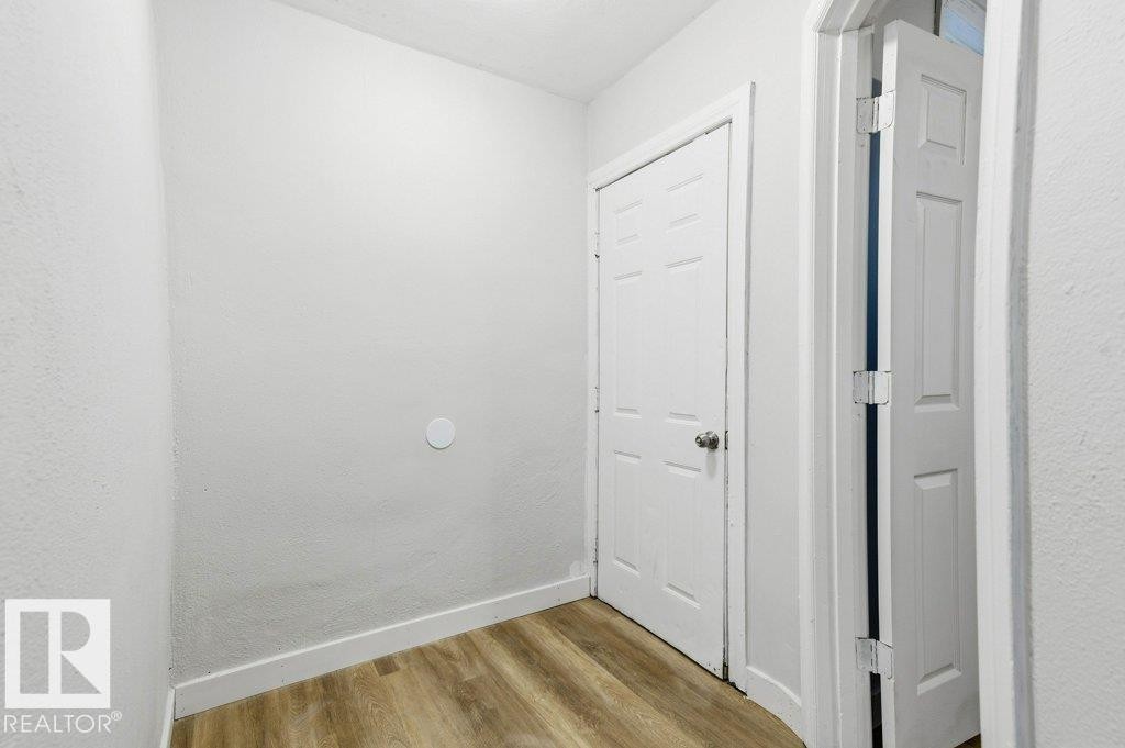 Hall featuring a textured wall and light wood finished floors - 10704 96 St Nw, Edmonton, AB - Indoor Photo Showing Other Room