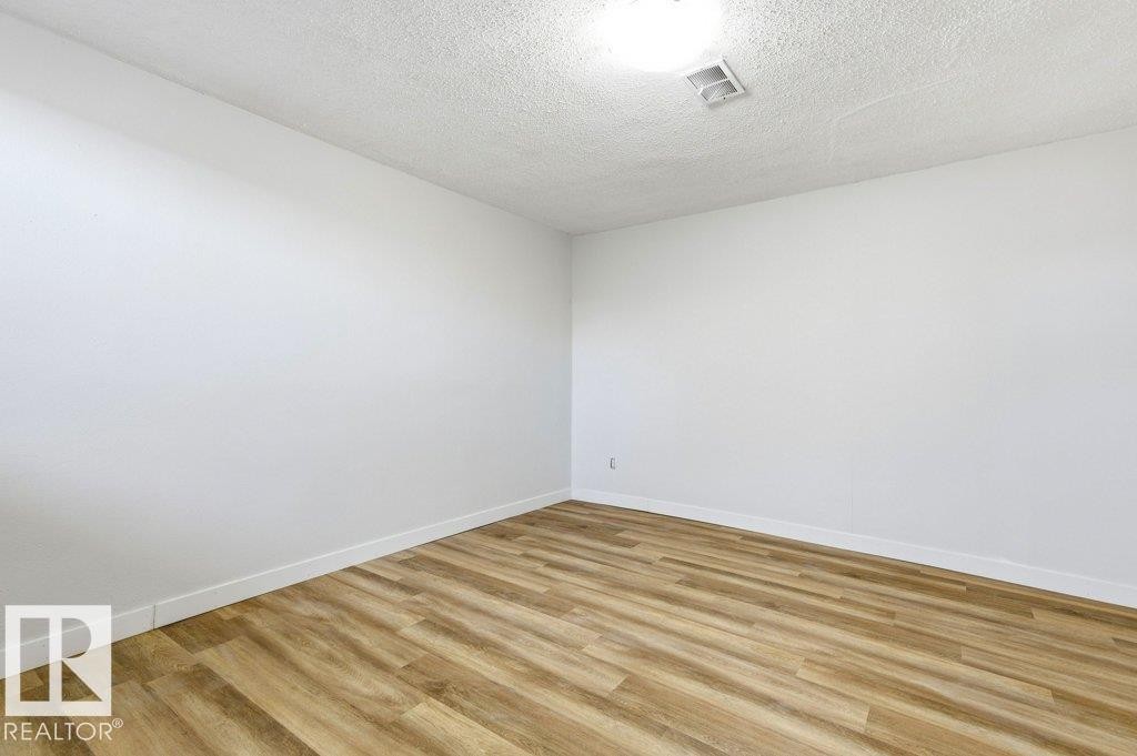 Spare room featuring wood finished floors and a textured ceiling - 10704 96 St Nw, Edmonton, AB - Indoor Photo Showing Other Room